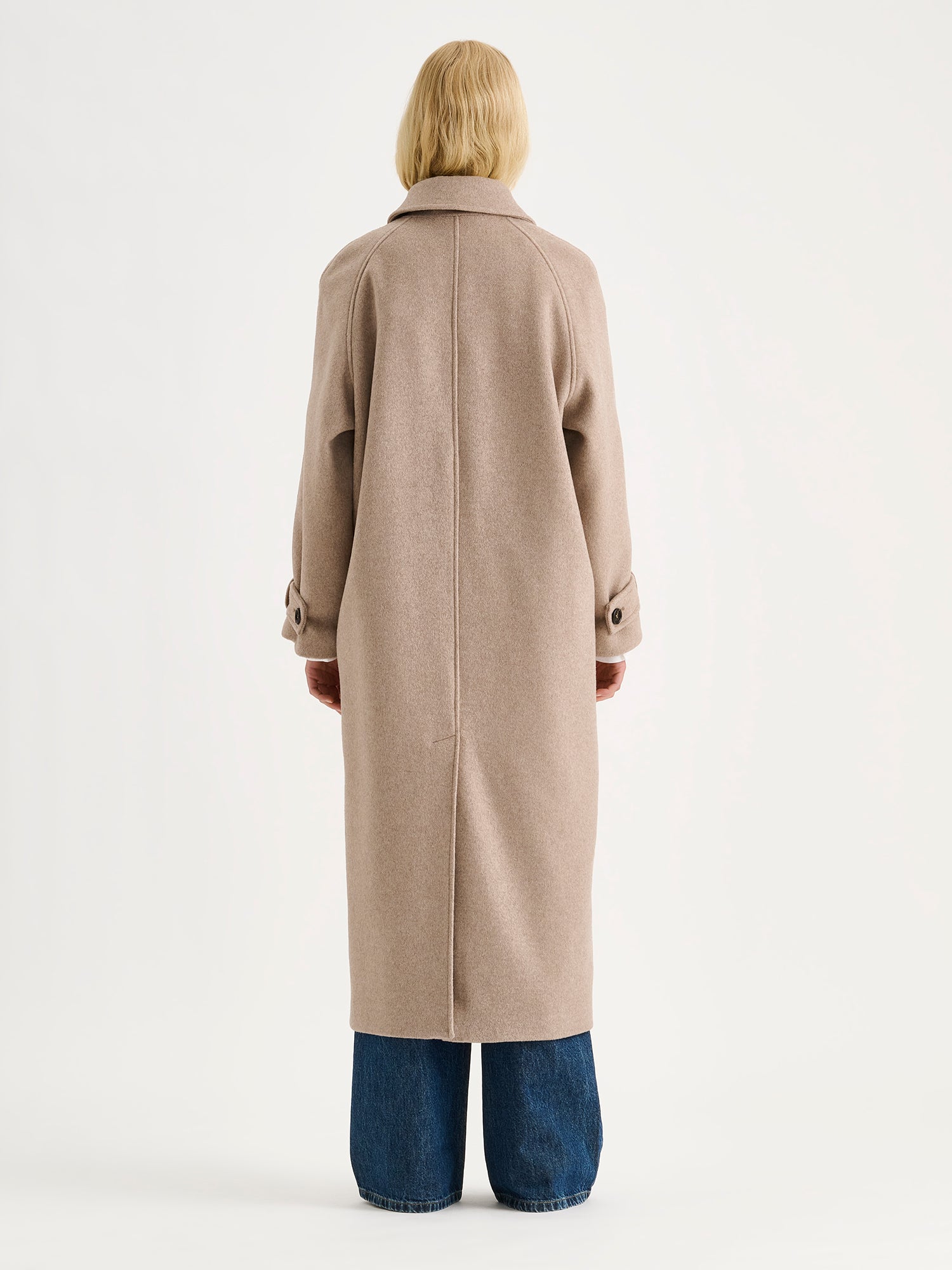 Nanso women's timelessly elegant and effortlessly classic, the Tove long wool coat in beige, on a model with blue jeans, from the backside