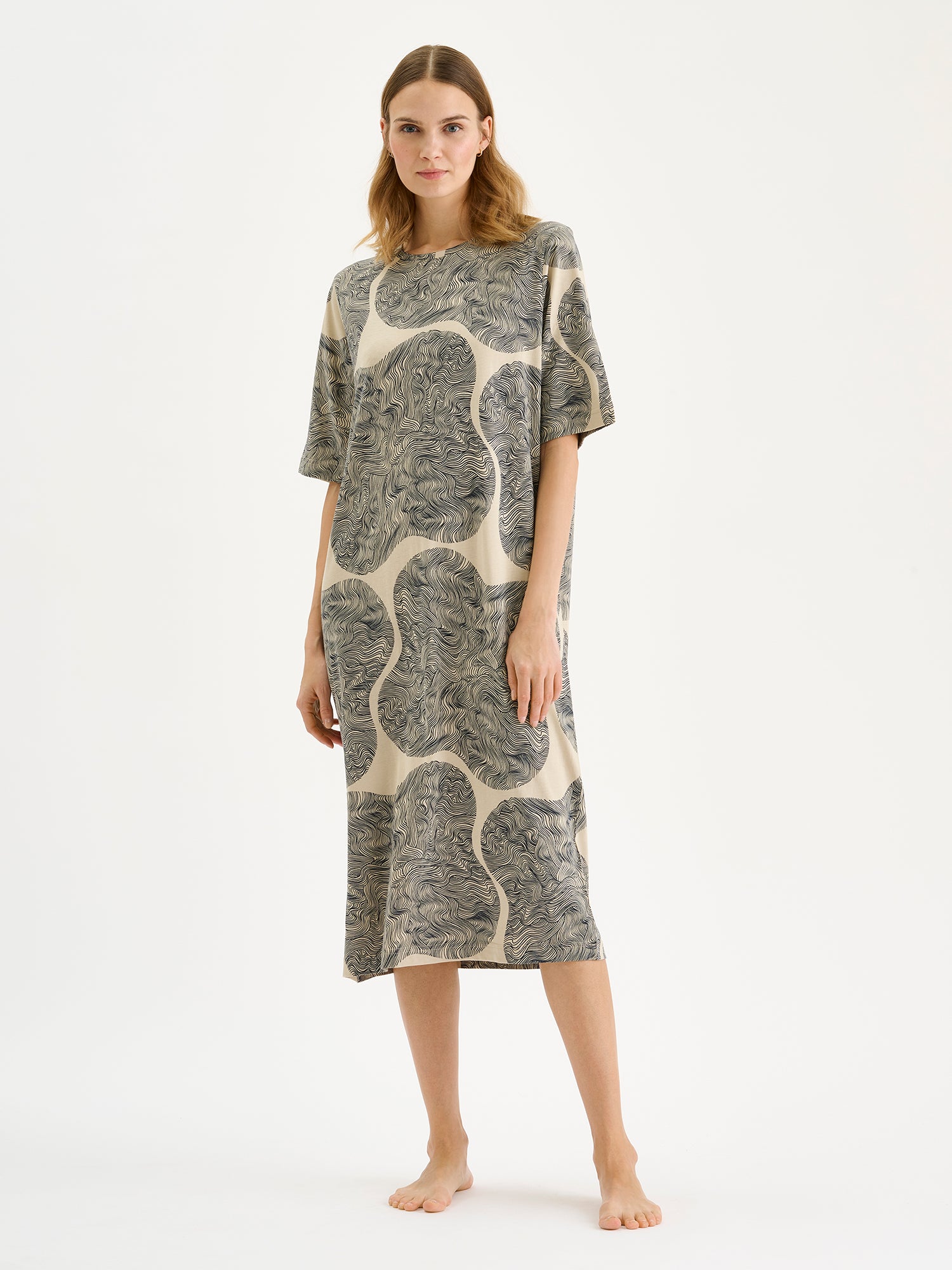 The relaxed, straight-cut Paasi nightdress for women with a harmonious beige-toned print, on a model.