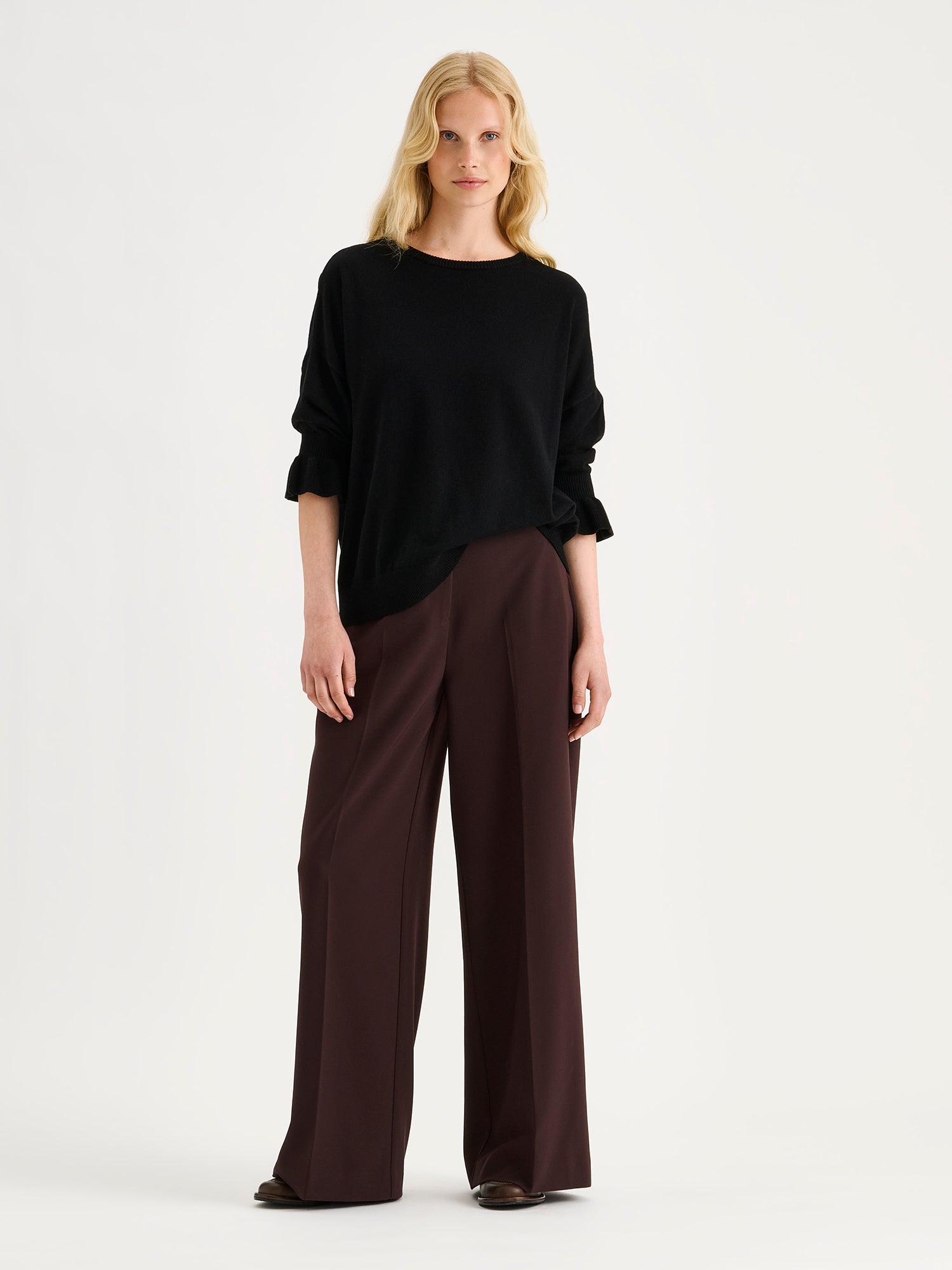 Nanso women's simply stylish and lightweight Villis Frilla knit jumper is charmingly finished with beautiful frill details at the cuffs, on a model with brown trousers