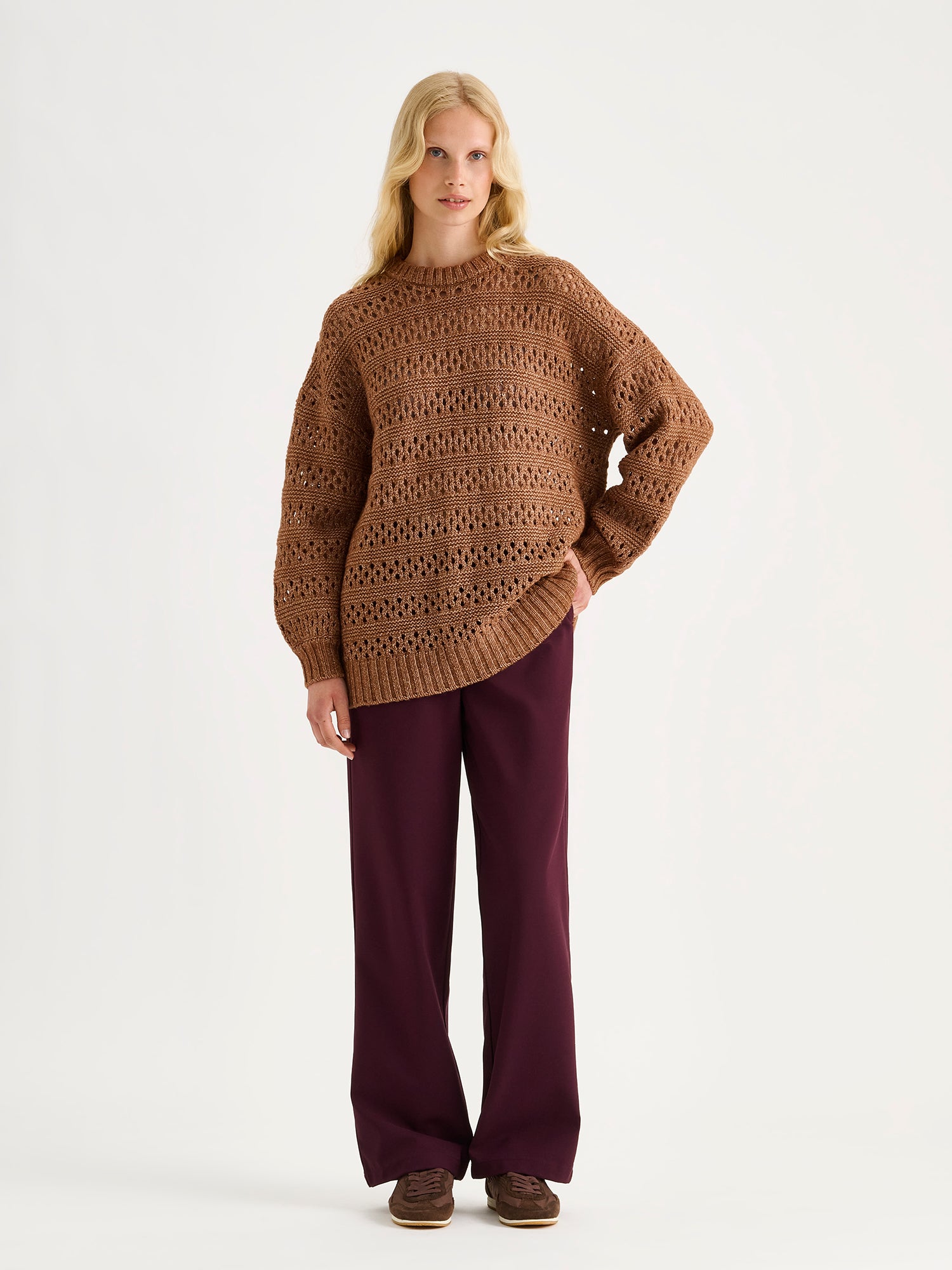 Nanso women's relaxed and on-trend, the Asta jumper combines the softness of a chunky knit with the airy lightness of an openwork, lace-like texture. Pictured on a model with red trousers