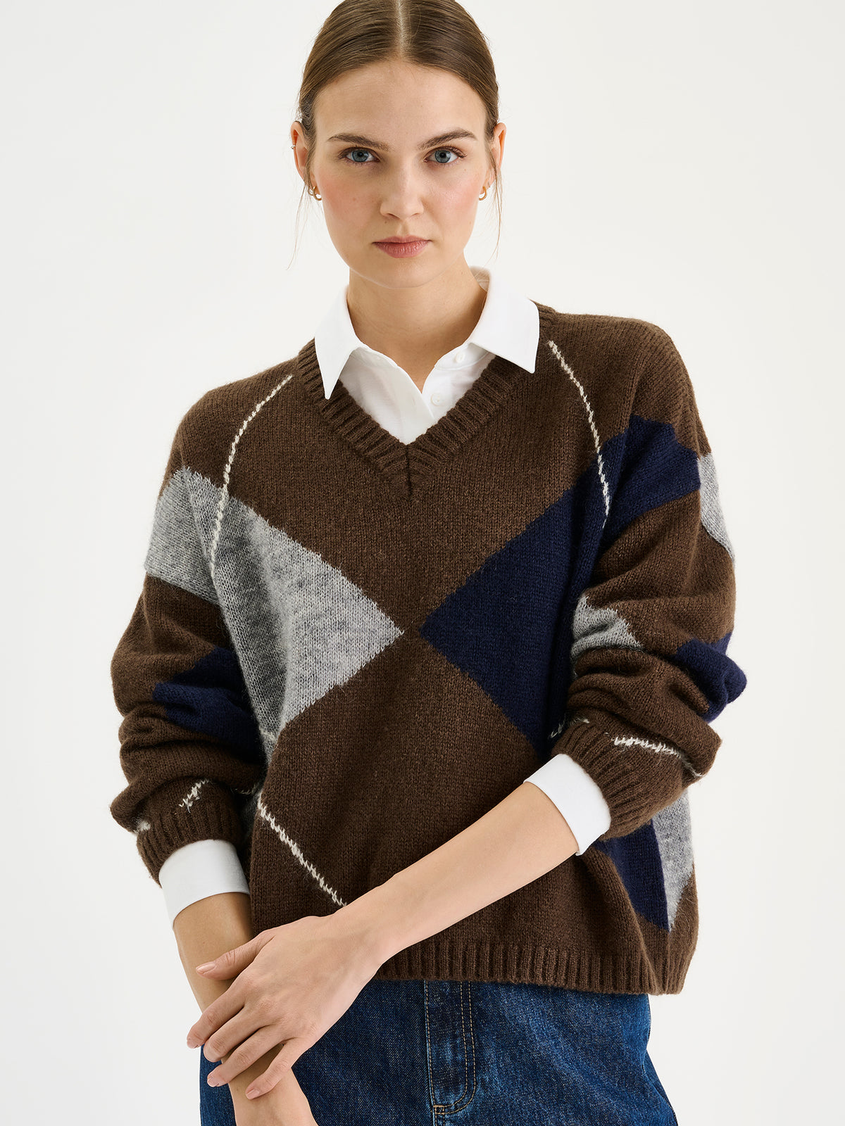 Nanso women's stylish Lotte knit sweater featuring a classic yet on-trend argyle pattern in rich autumnal shades, on a model with jeans, close-up.