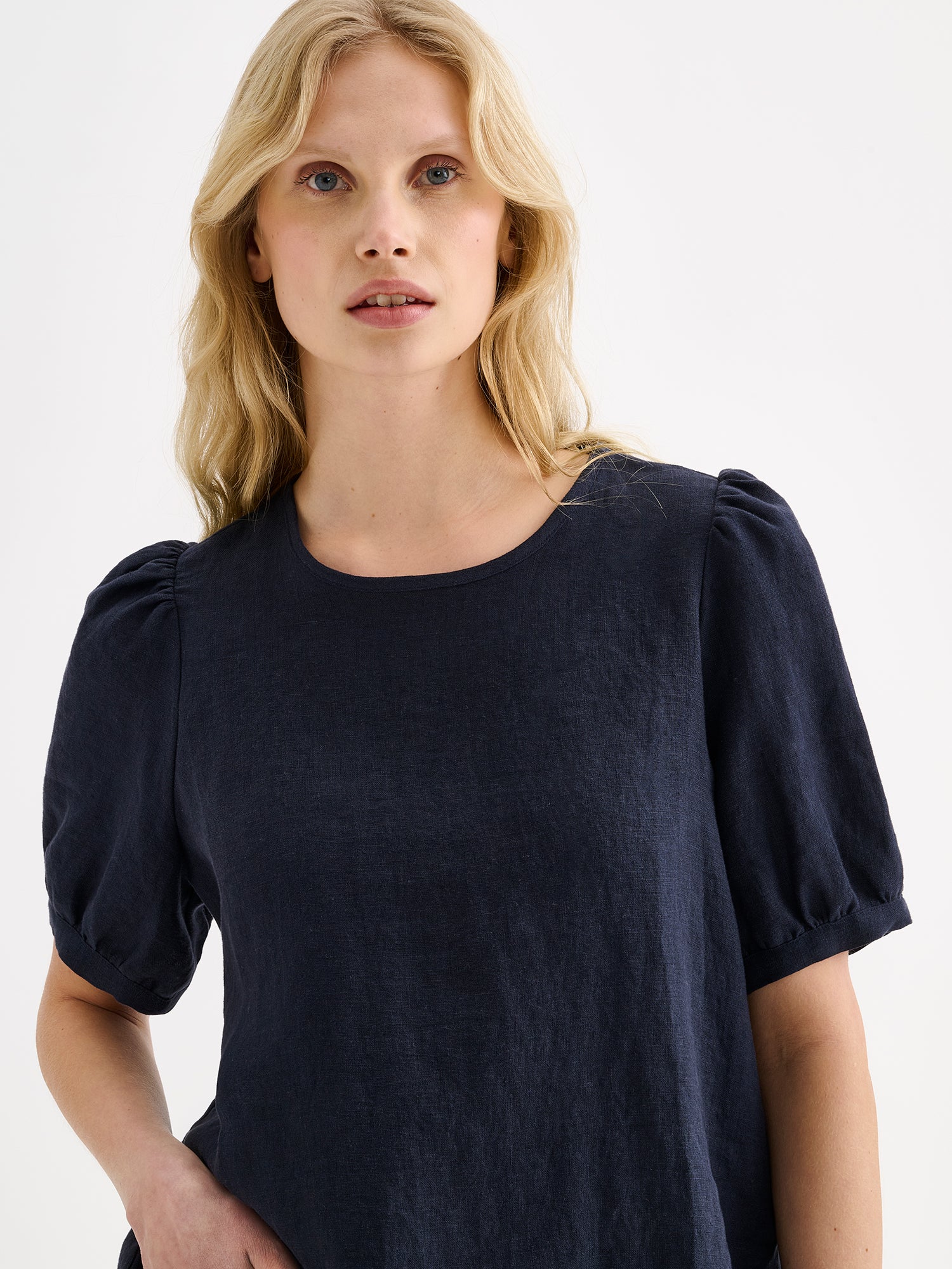 Nanso women's dark blue breathable Sarastus linen blouse featuring short puffed sleeves on a model close-up.