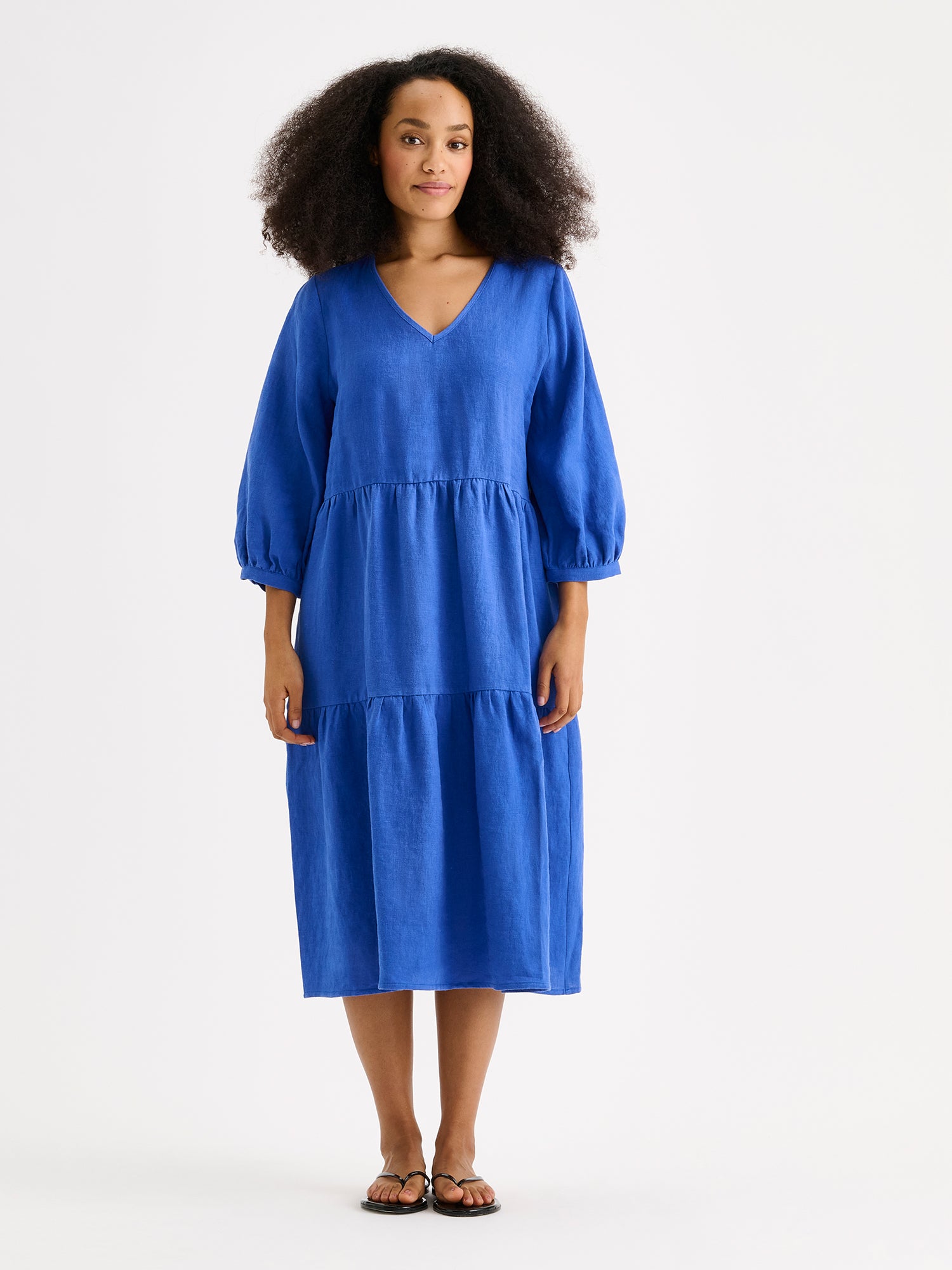 Nanso women's SARALIVIA linen dress in blue features charming layered ruffles, 3/4 sleeves, side pockets and a V-neckline. Pictured on a model.