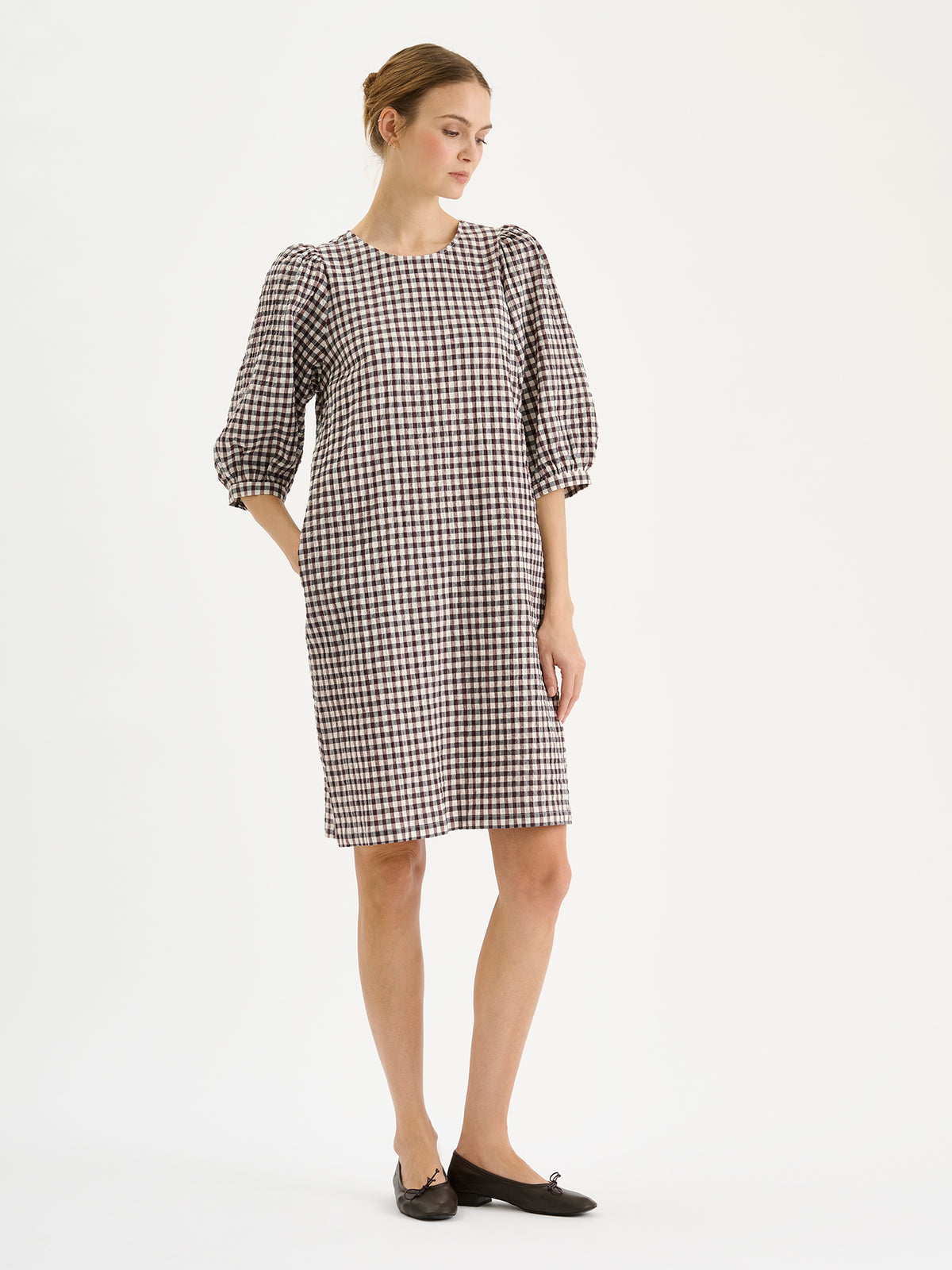 Nanso women's Treffit dress in a timeless brown and white check pattern, on a model with sneakers.