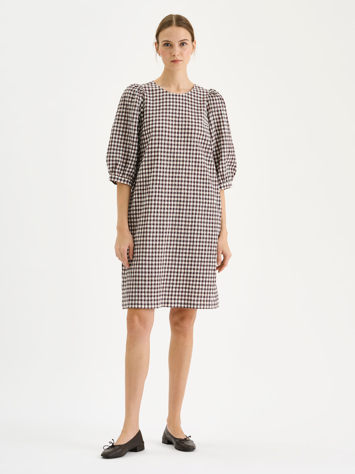 Nanso women's Treffit dress in a timeless brown and white check pattern, on a model with ballerinas.