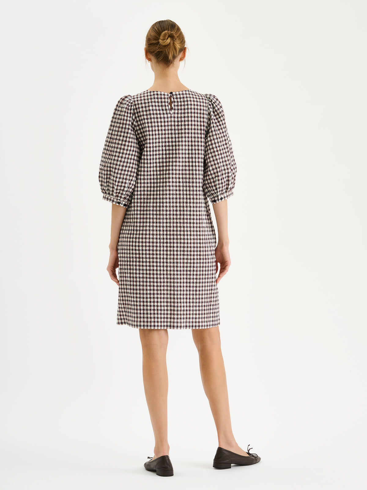 Nanso women's Treffit dress in a timeless brown and white check pattern, on a model with ballerinas, backside.
