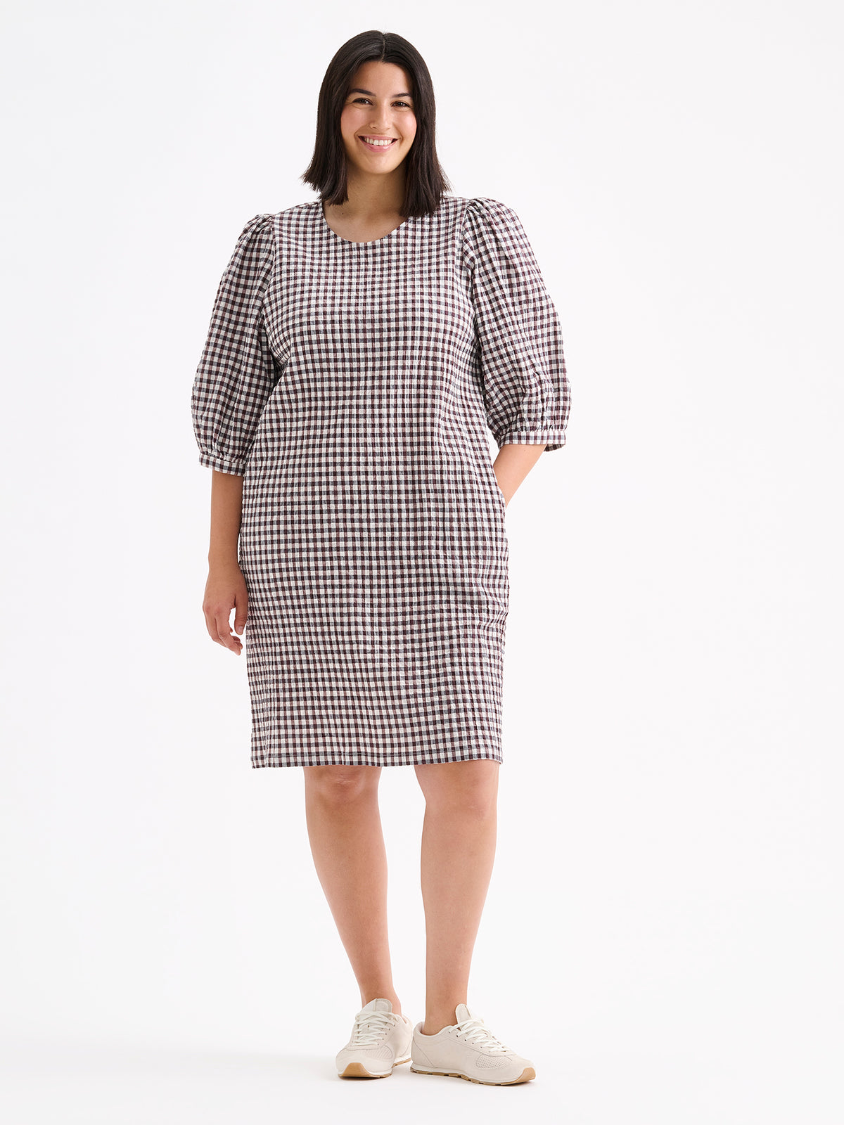 Nanso women's Treffit dress in a timeless brown and white check pattern, on a model with sneakers.