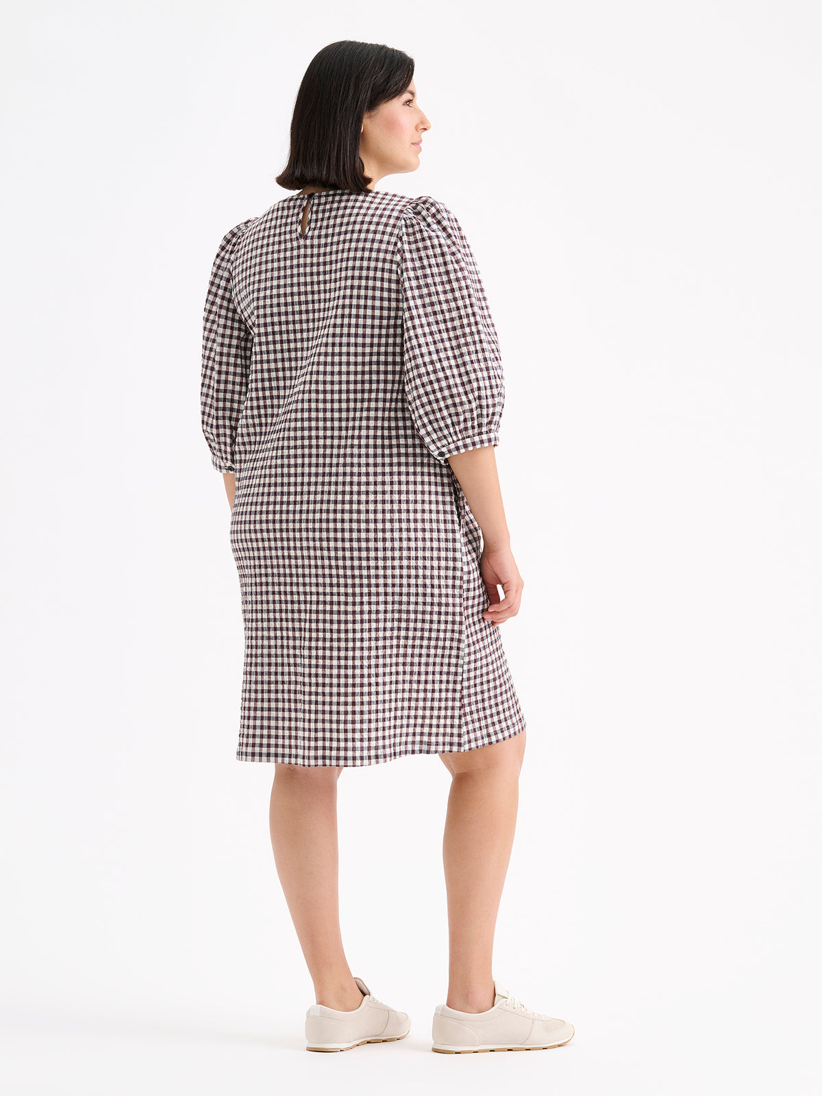 Nanso women's Treffit dress in a timeless brown and white check pattern, on a model with sneakers, from the backside.