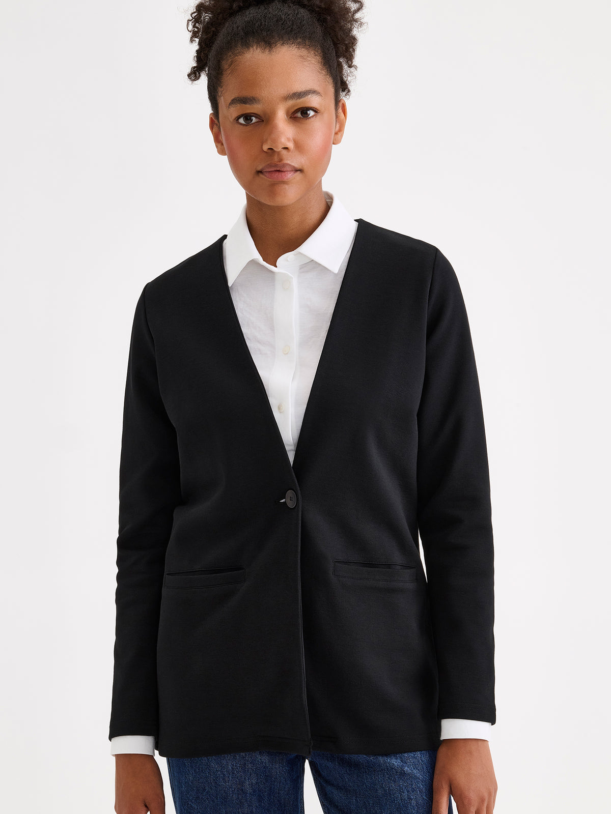 Nanso women's black collarless Nerea jersey blazer on a model with a white button-up shirt and jeans.