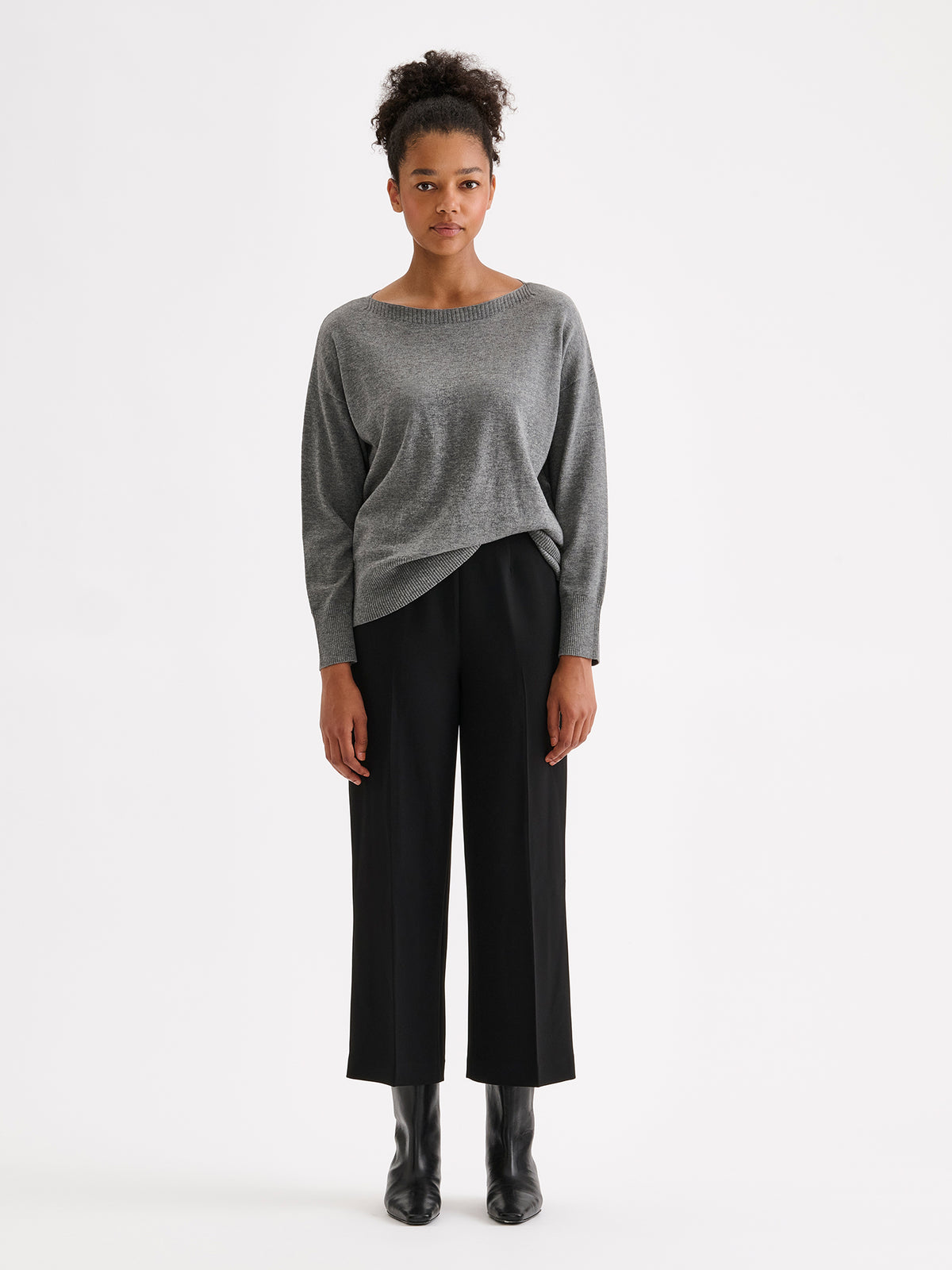 Nanso women’s black Avelia culottes trousers with pockets and pressed creases, on a model with a gray sweater.