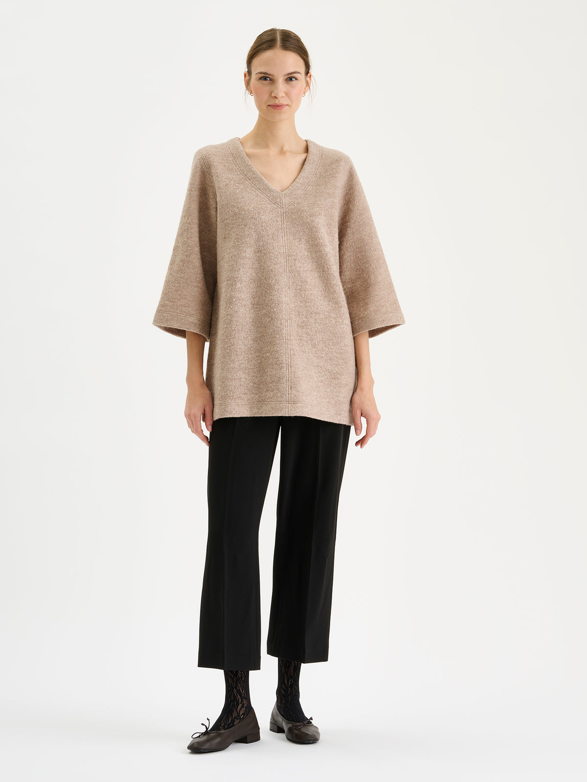 Nanso women’s black Avelia culottes trousers with pockets and pressed creases, on a model with a beige tunic.