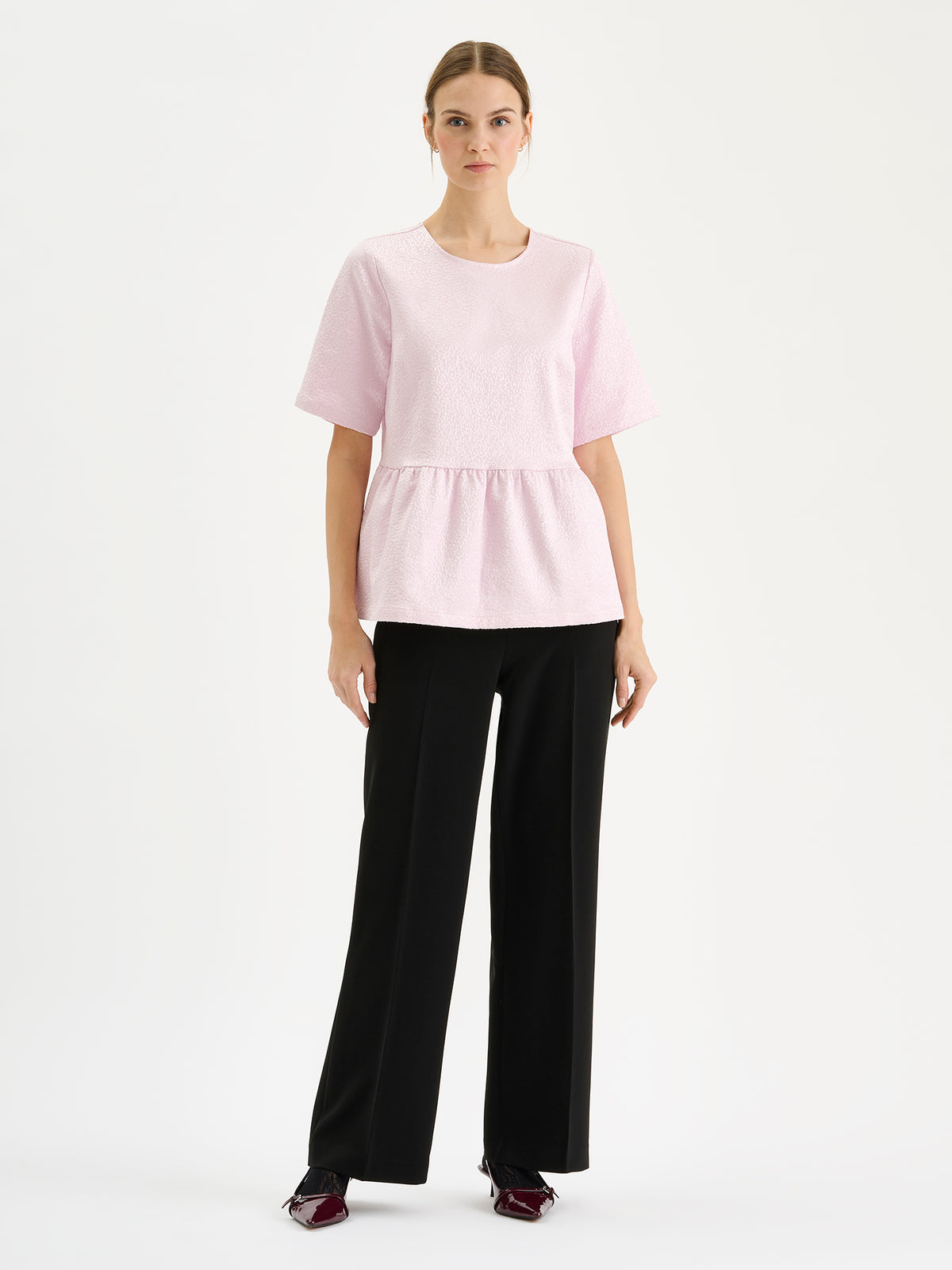Nanso women’s black Avelia trousers with pockets and pressed creases, on a model with a pink top