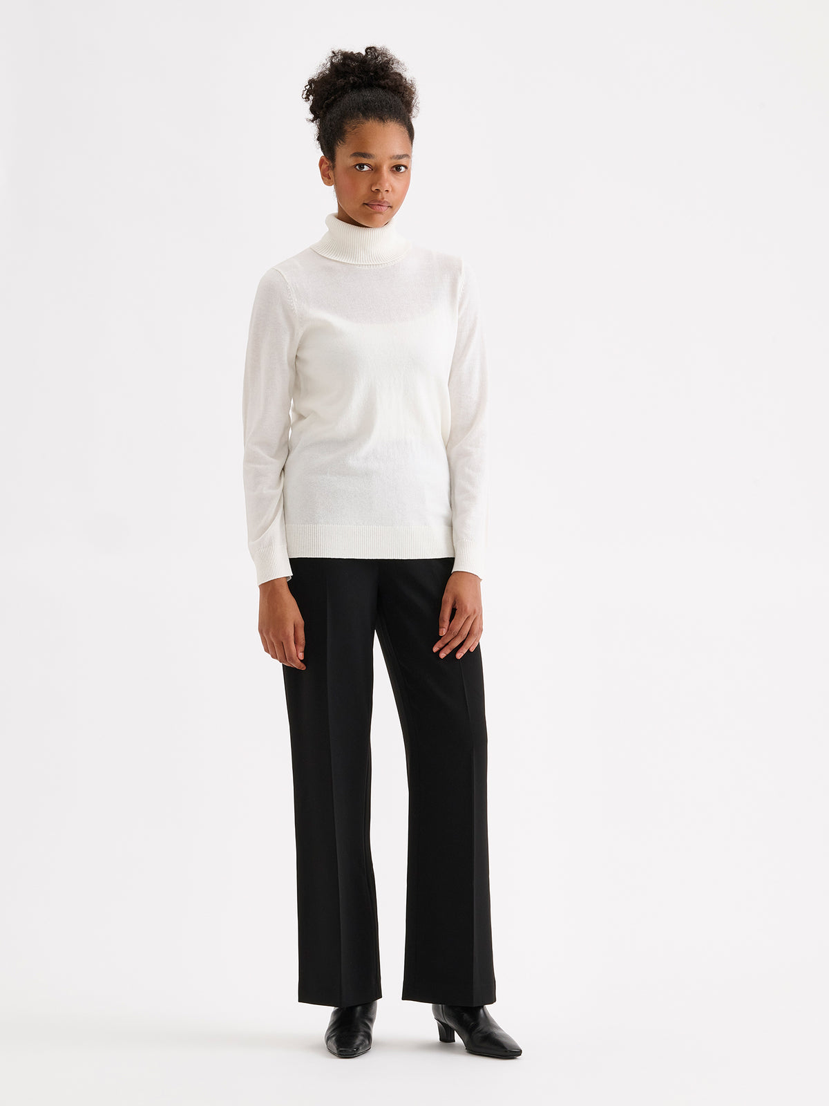 Nanso women’s black Avelia trousers with pockets and pressed creases, on a model with a white top
