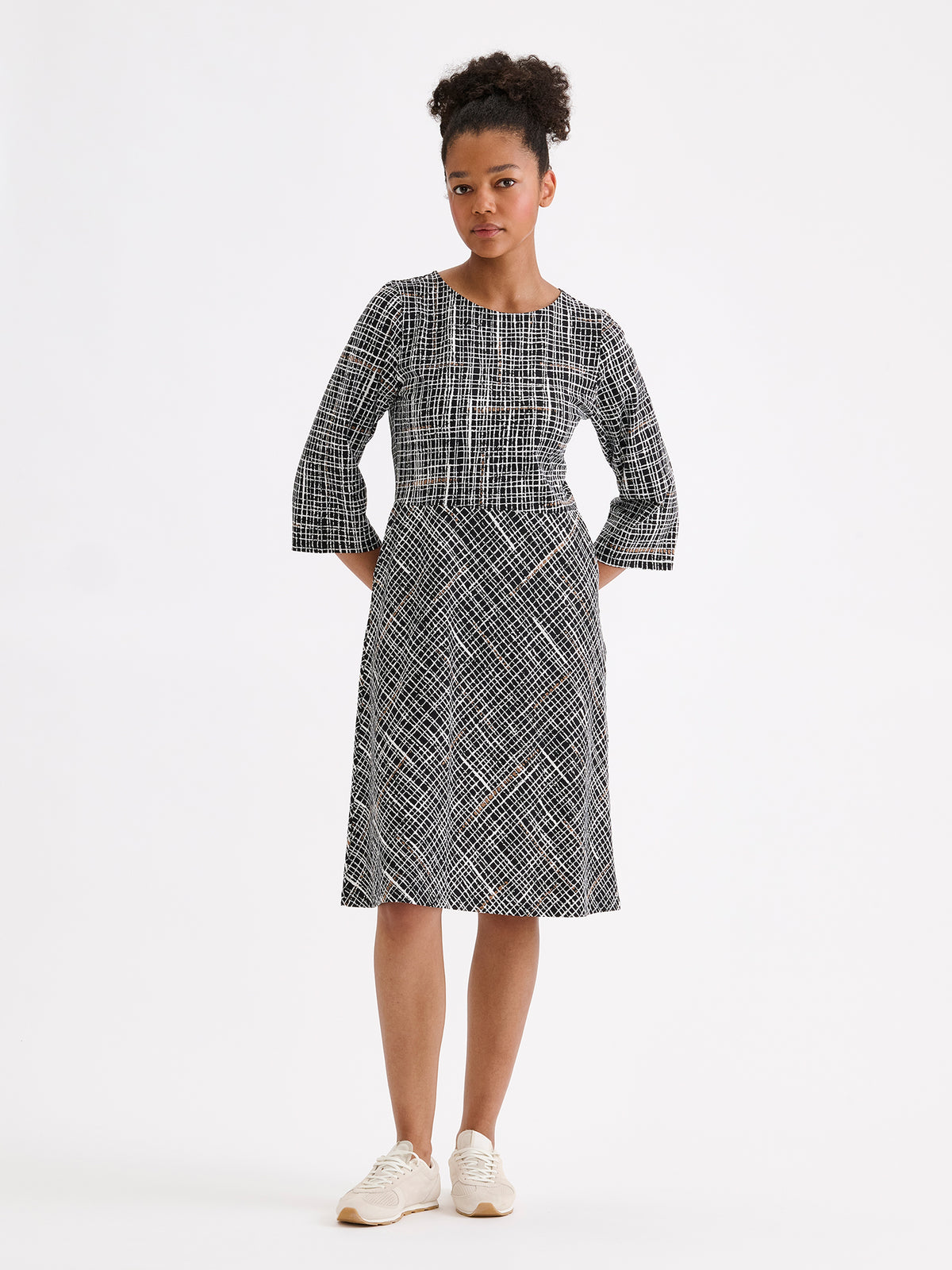 Nanso women's Ristikko jersey dress features a stylish graphic black-and-white check pattern, picture on a model with sneakers.