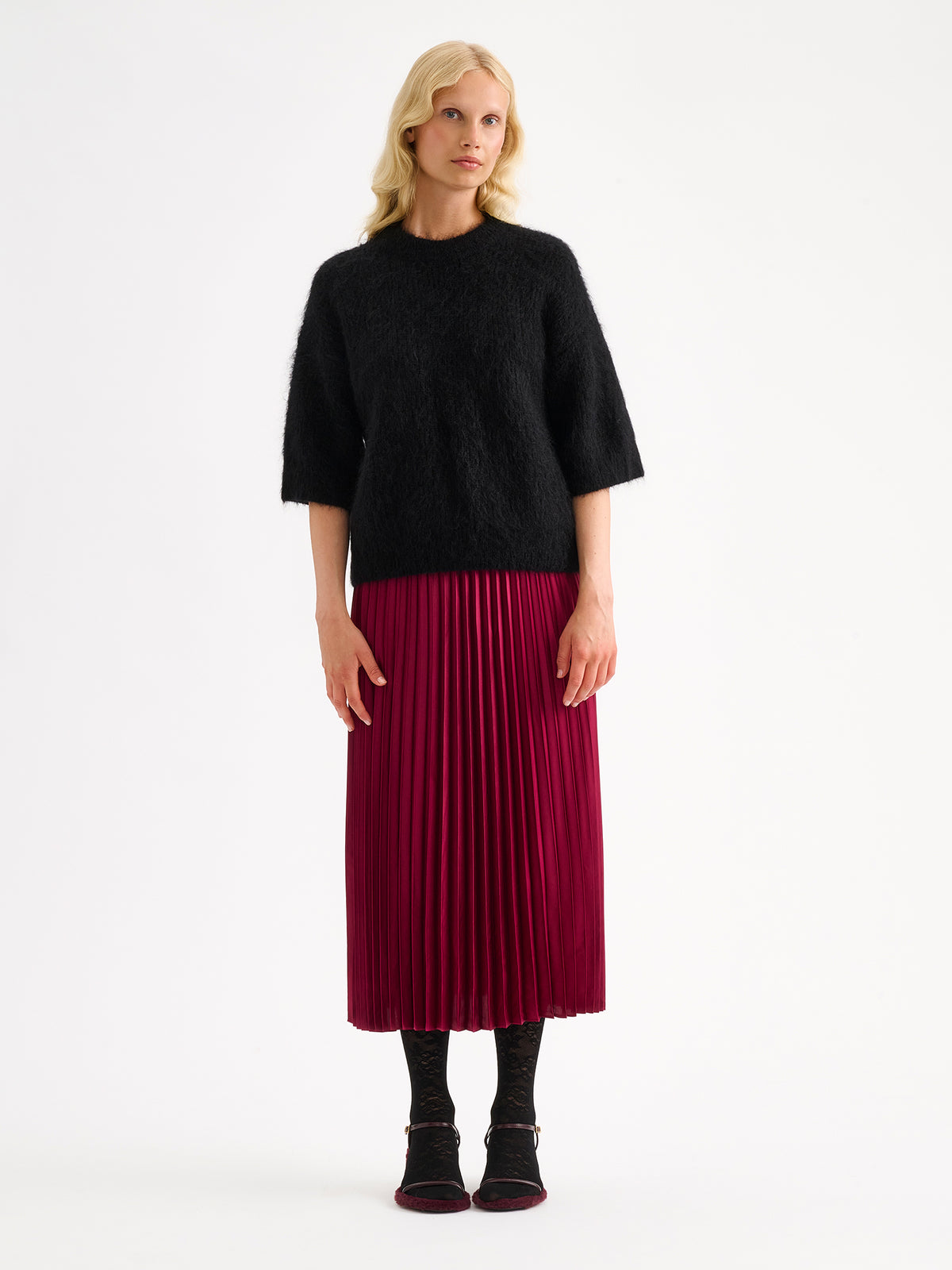 Nanso women's wonderfully warm and luxurious Sumi knitted sweater in classic black and beautifully fluffy texture. Pictured on a model with a violet pleated skirt. | S - 174cm