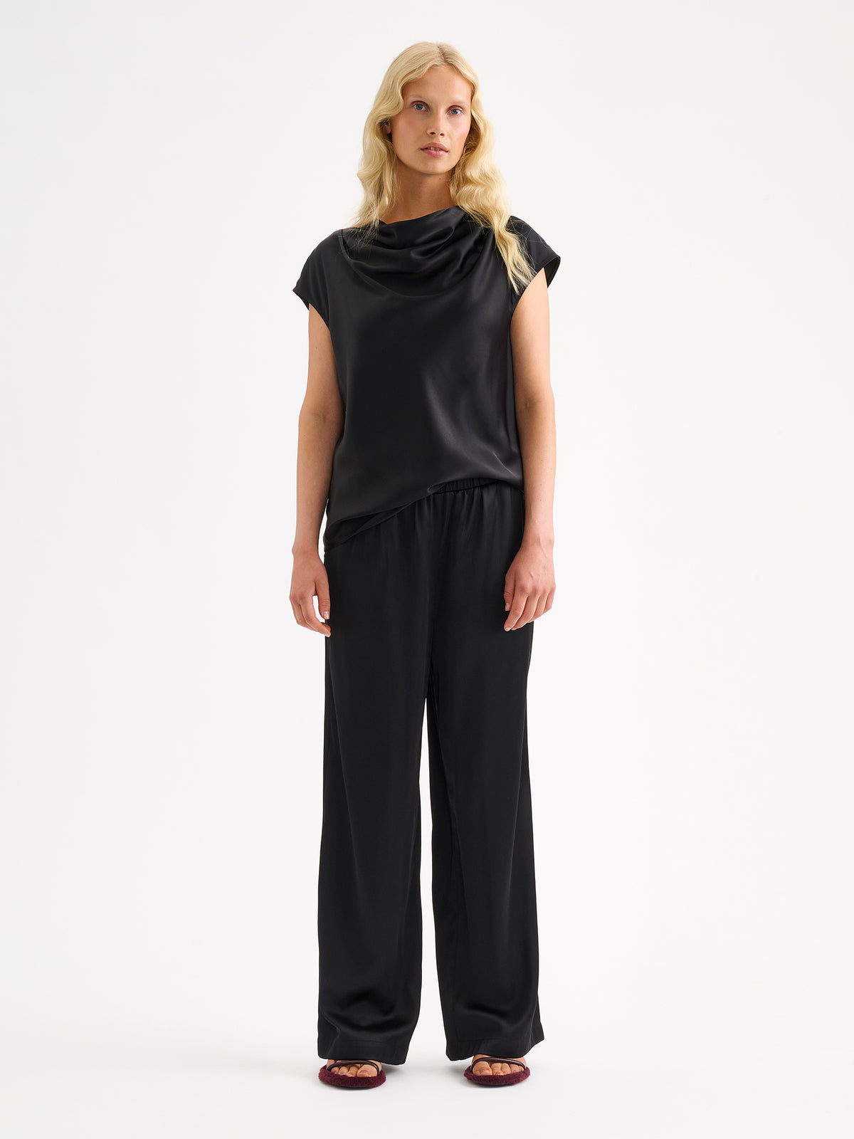 Nanso women's elegant Silva satin blouse in a classic black  shade on a model with matching satin trousers.