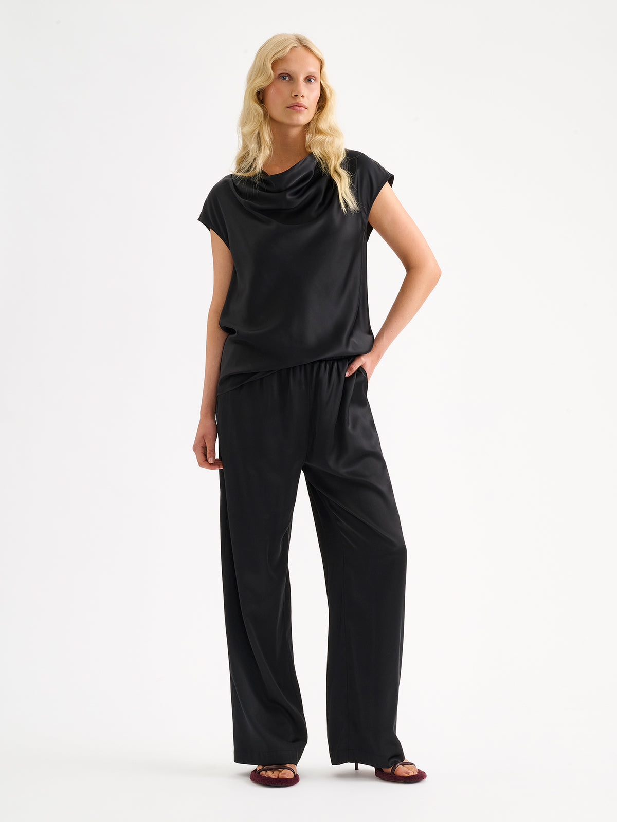 Nanso women's elegant Silva satin blouse in a classic black  shade on a model with matching satin trousers.