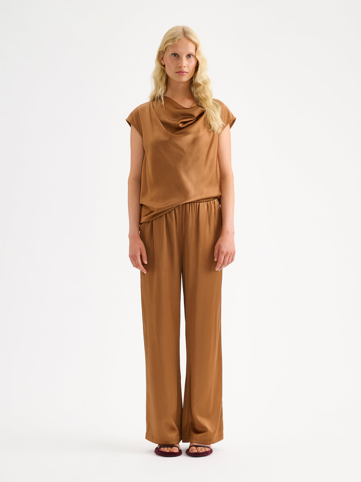 Nanso women's elegant Silva satin blouse in a radiant brown shade is a versatile wardrobe favourite for the season's celebrations. On a model with matching satin trousers.