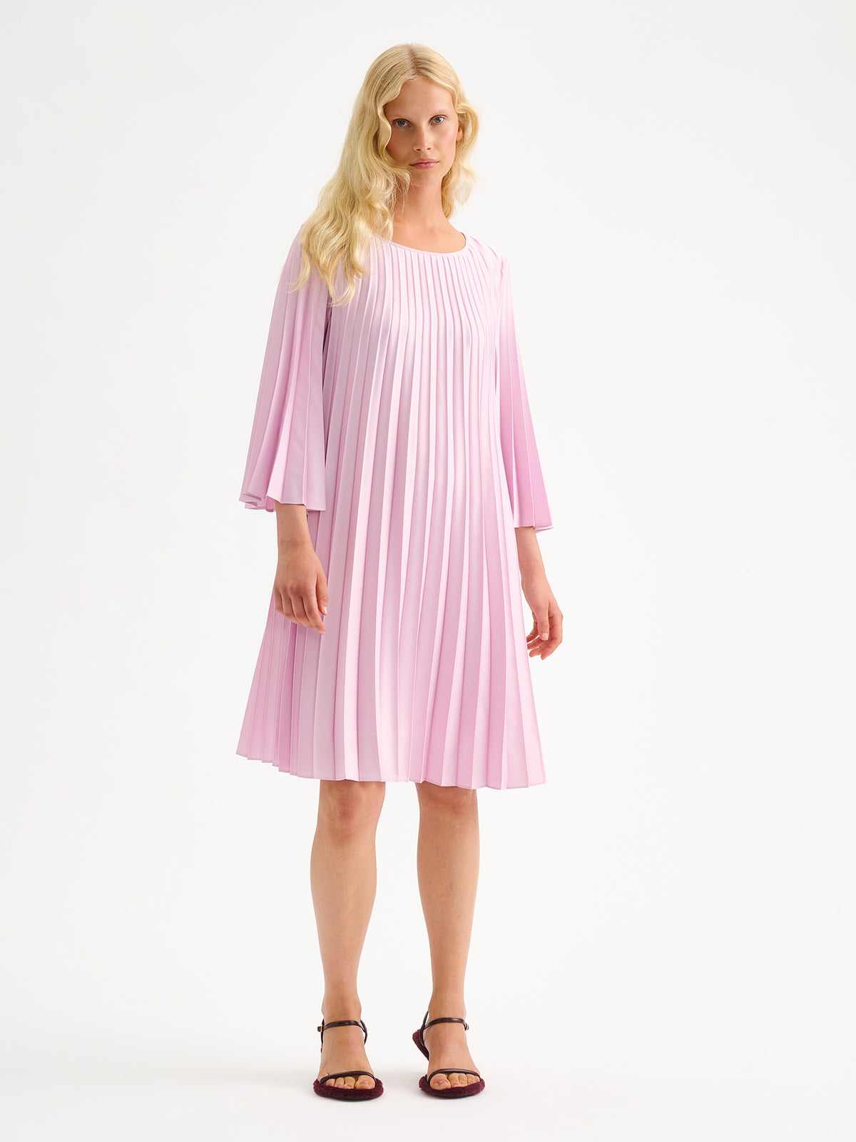 Nanso women's beautifully draping Taite dress in a deliciously cool light pink shade. This versatile pleated dress can be worn with or without the slim belt. This A-line dress features 3/4-length sleeves and a slim belt at the waist. Pictured on a model with heels without the belt.