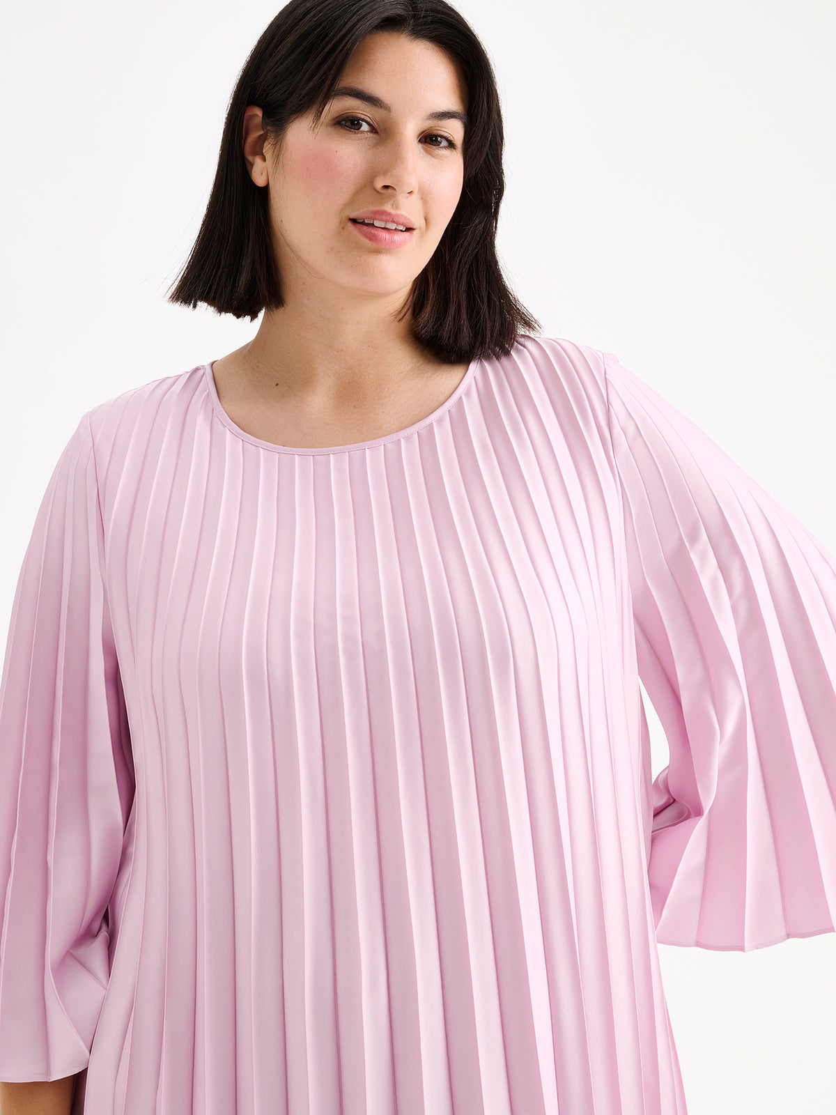 Nanso women's beautifully draping Taite dress in a deliciously cool light pink shade. This versatile pleated dress can be worn with or without the slim belt. This A-line dress features 3/4-length sleeves and a slim belt at the waist. Pictured on a model close-up.