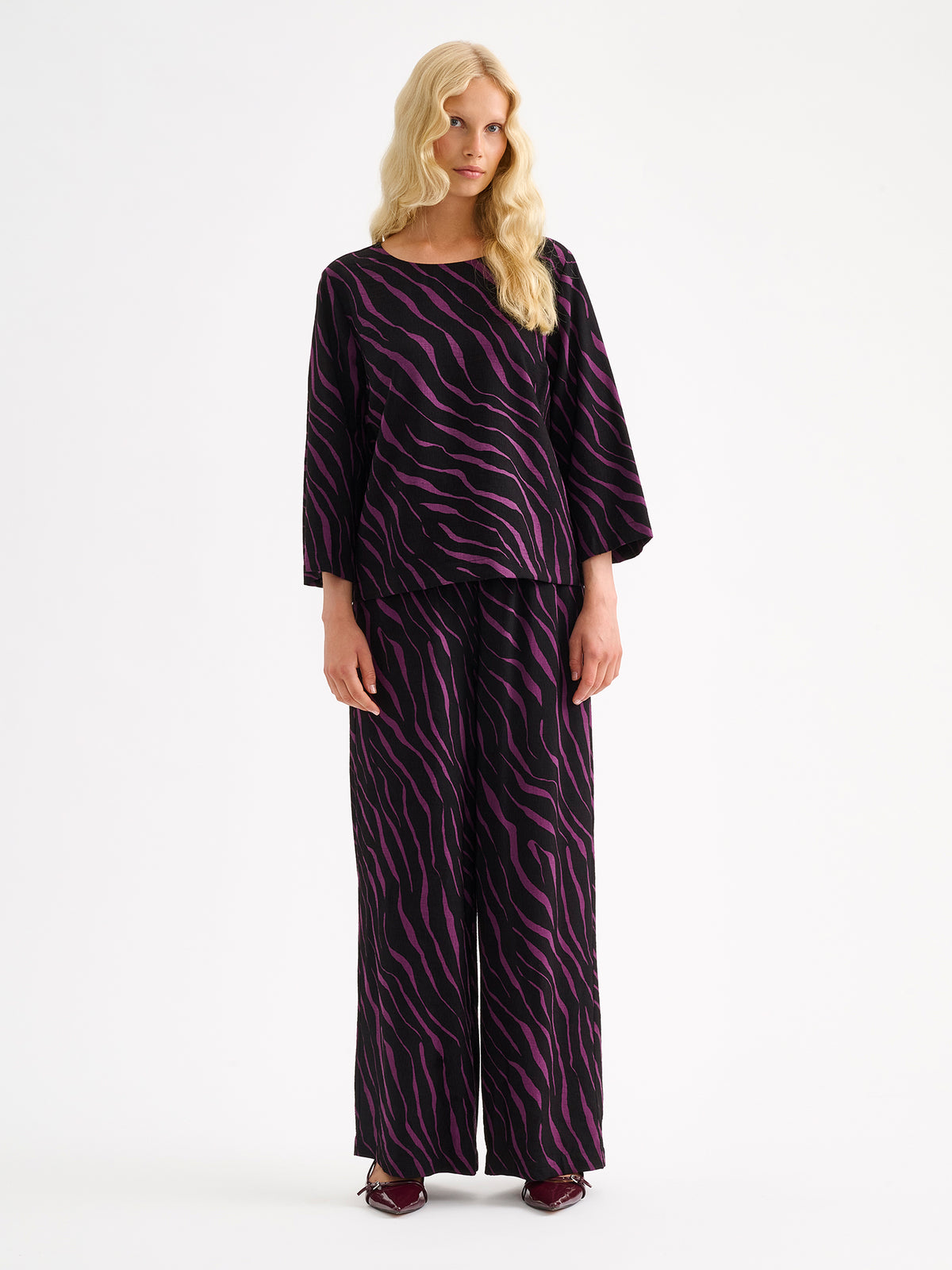 Nanso women's striking Sypressi trousers combine beautifully draping fabric with a trendy wide-leg silhouette, on a model with a matching blouse. | 36 - 174cm