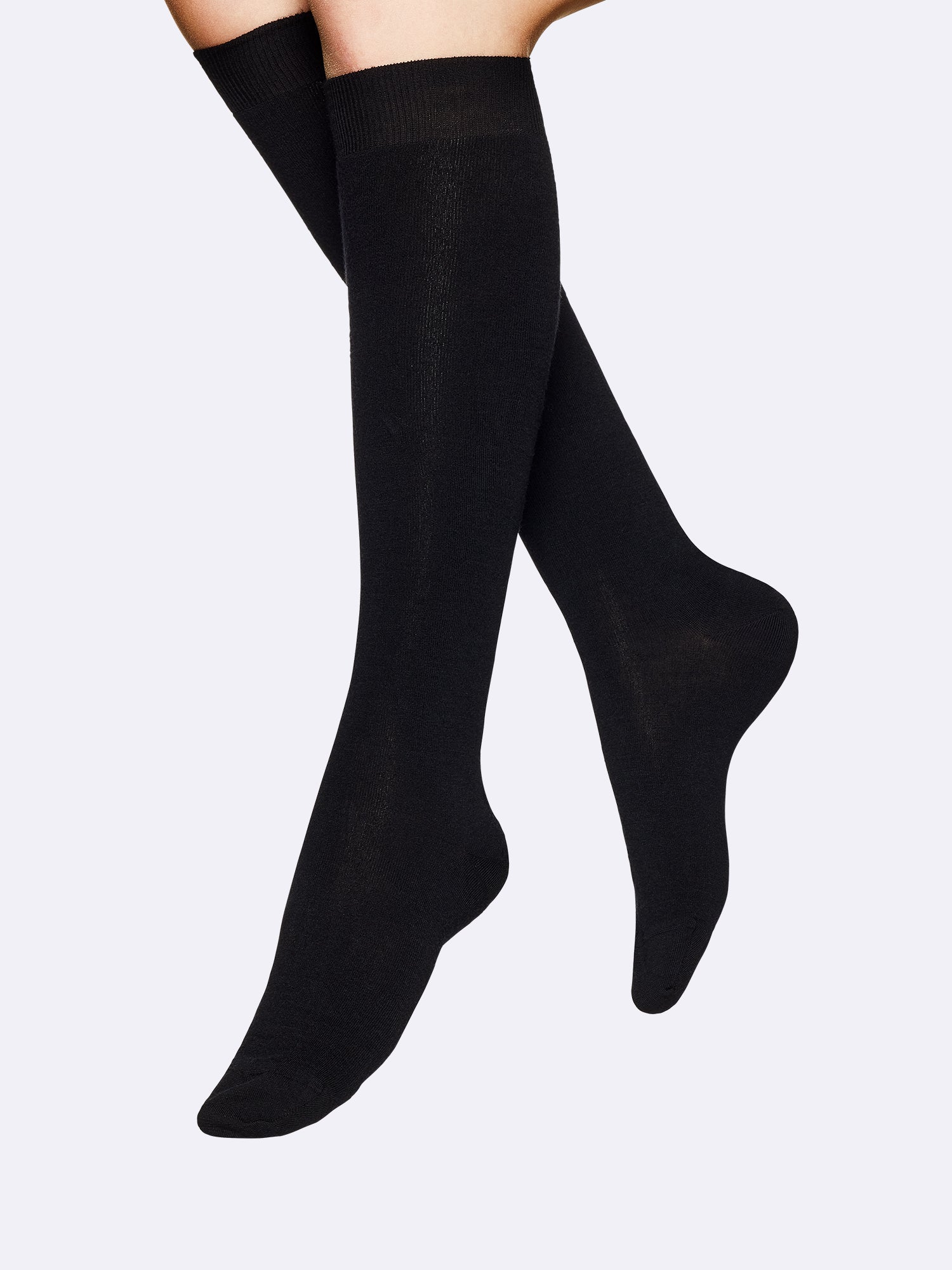 Women's black knee high Merino Wool socks crafted from a premium merino wool blend. Seamlessly constructed at the toe for a smooth fit. On a model, close up.