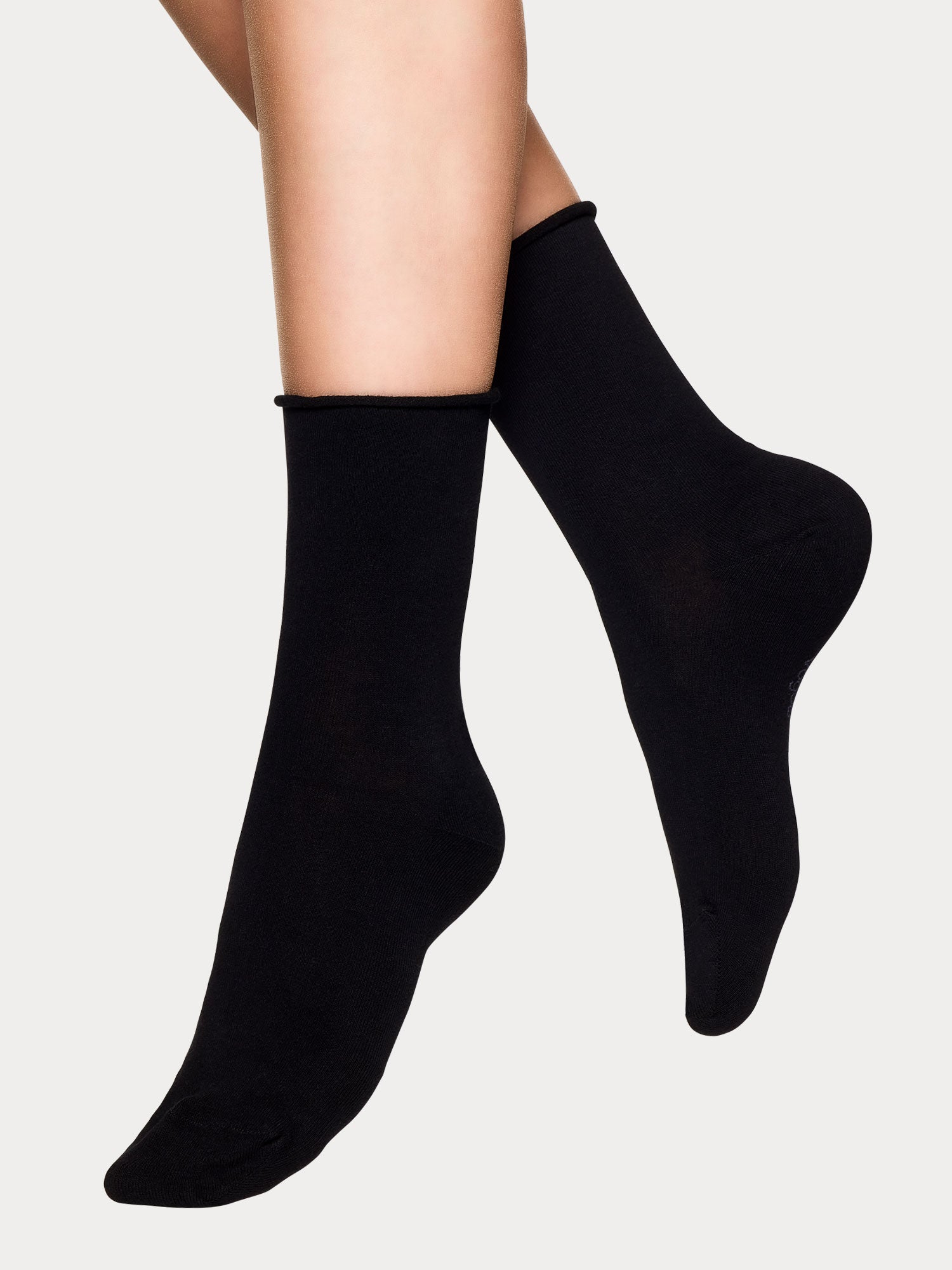 Vogue women's Cotton Comfort 2-pack of white and black cotton ankle socks. Crafted from premium cotton with a gentle rolled edge cuff. Black pair on a model.