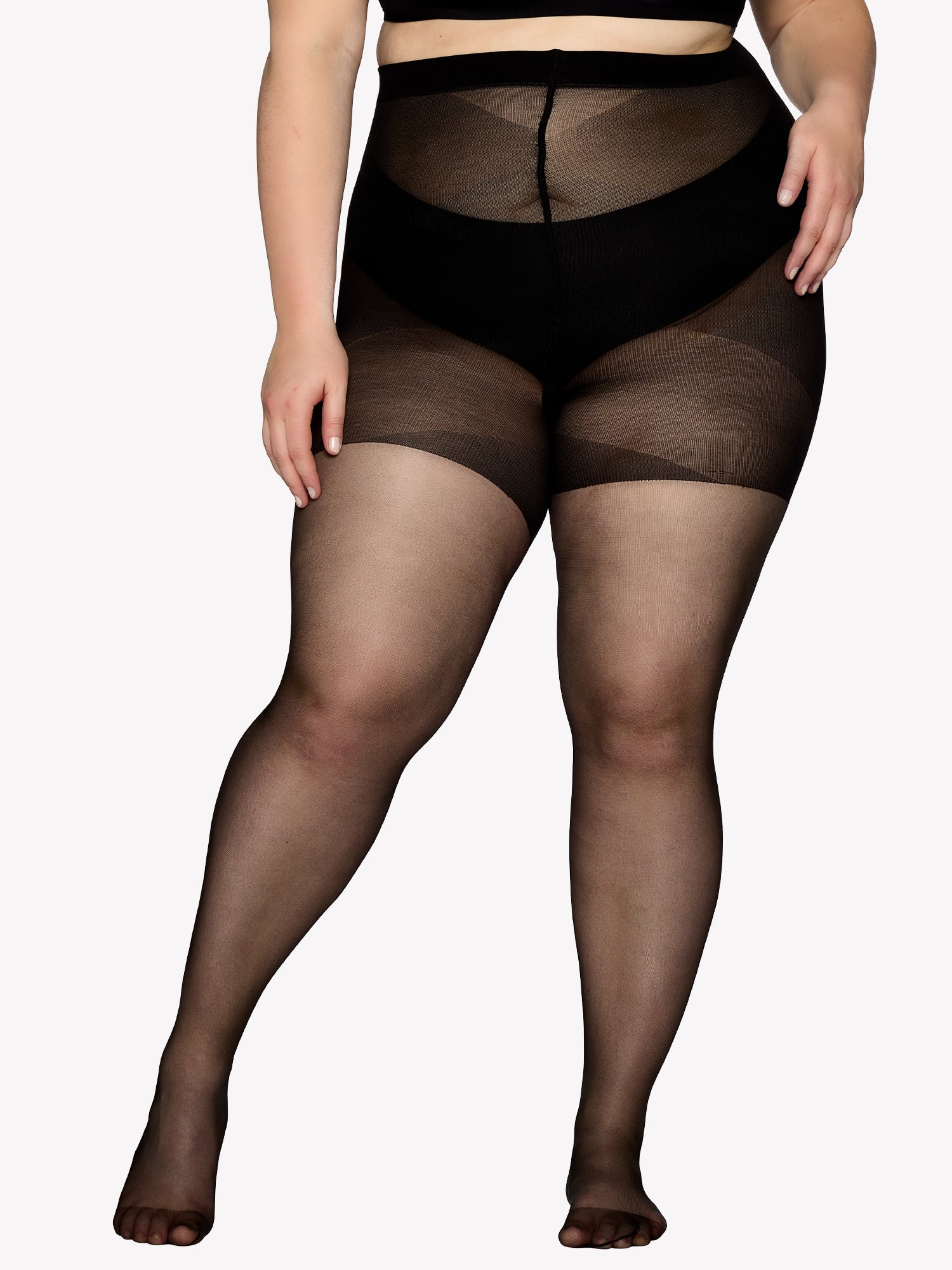 Vogue women's Curvy black 20 denier semi-matte tights for curvy figures. The elastic waistband sits comfortably, while the lightweight gusset design ensures easy dressing. On a model from the front.