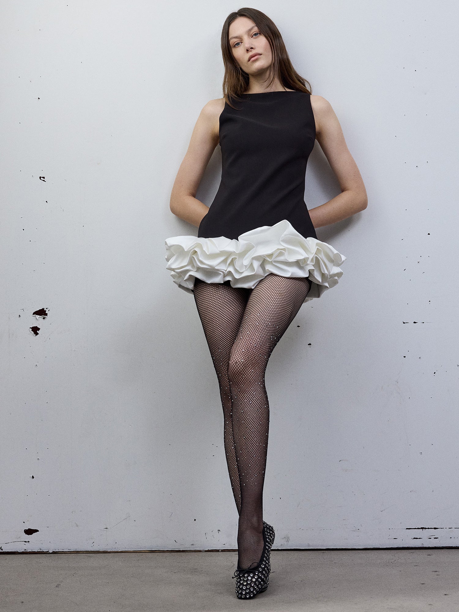 Vogue's black fishnet tights with sparkling diamonds combined with a black dress and shoes on a model standing in the picture.