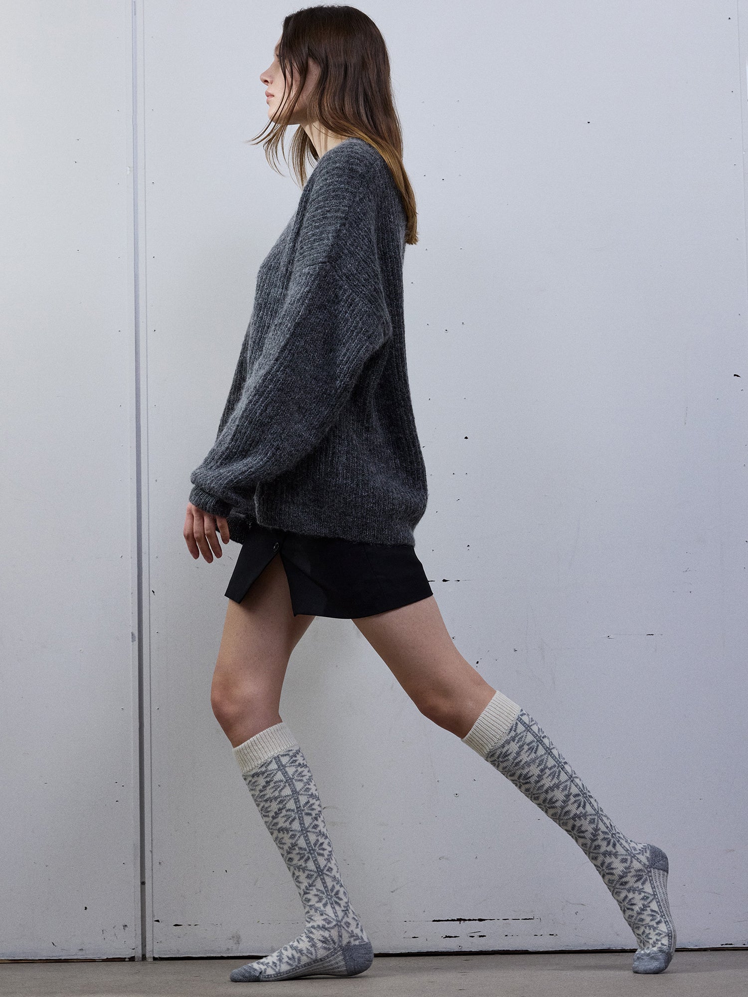 Model wearing a dark gray sweater and patterned off-white knee-high socks in the photo.