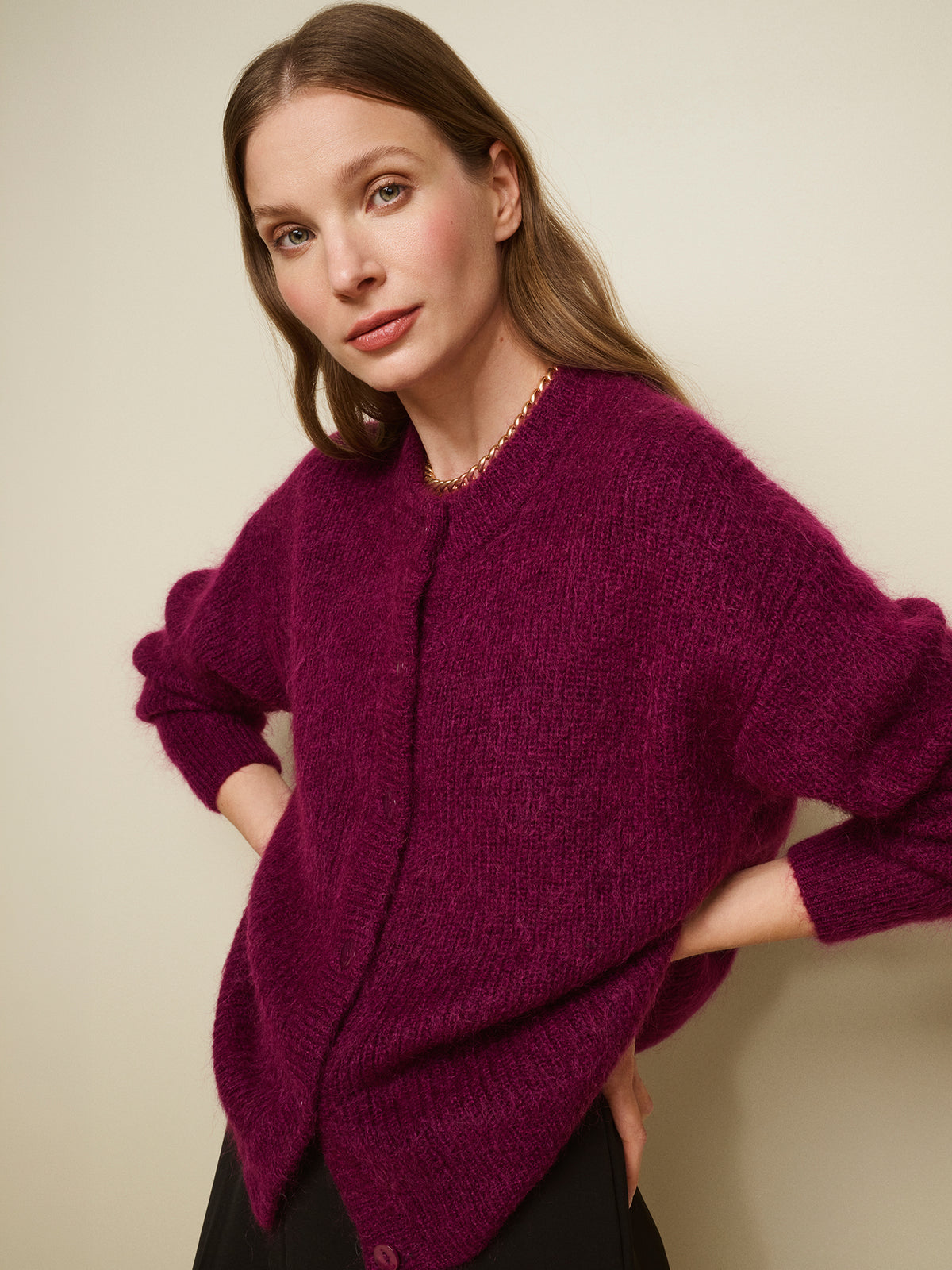 Nanso women's wonderfully warm and luxurious Sumi cardigan enchants with its vibrant violet hue and beautifully fluffy texture, pictured on a model with black trousers.