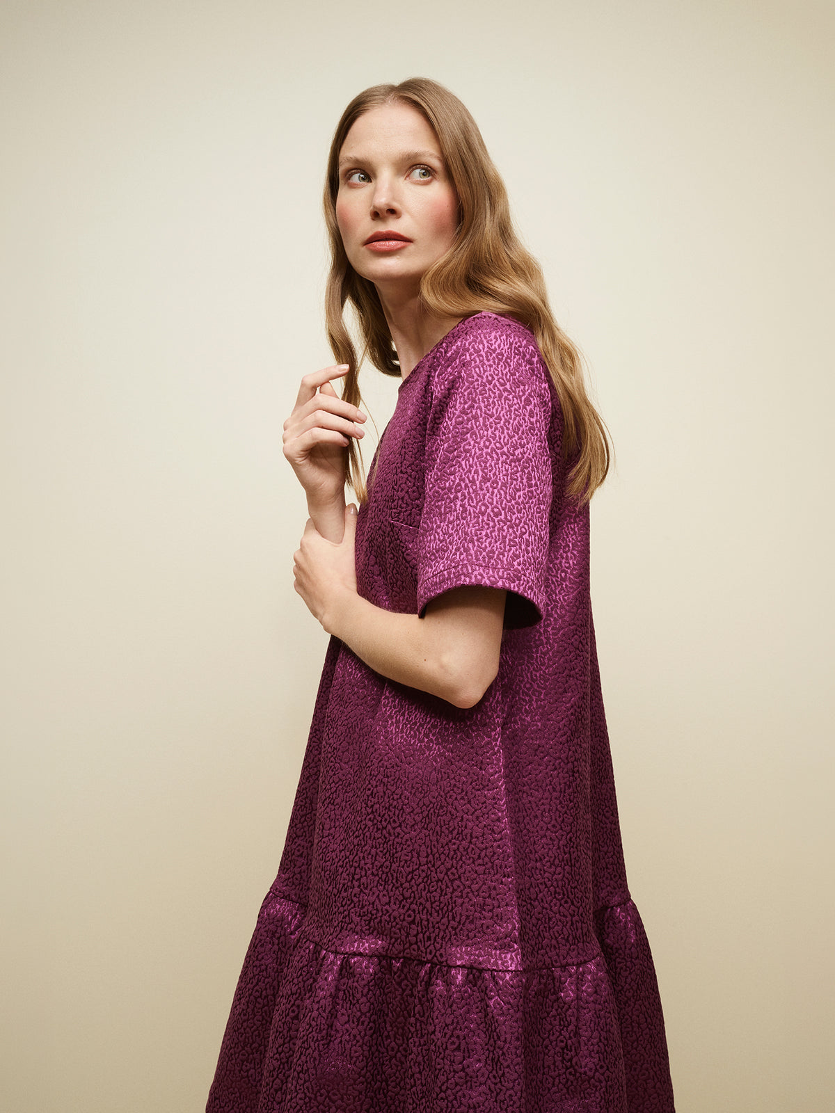 Nanso women's striking Leora dress captivates with its beautiful fabric, combining a festive sheen with a rich textured surface, pictured on a model, close-up.