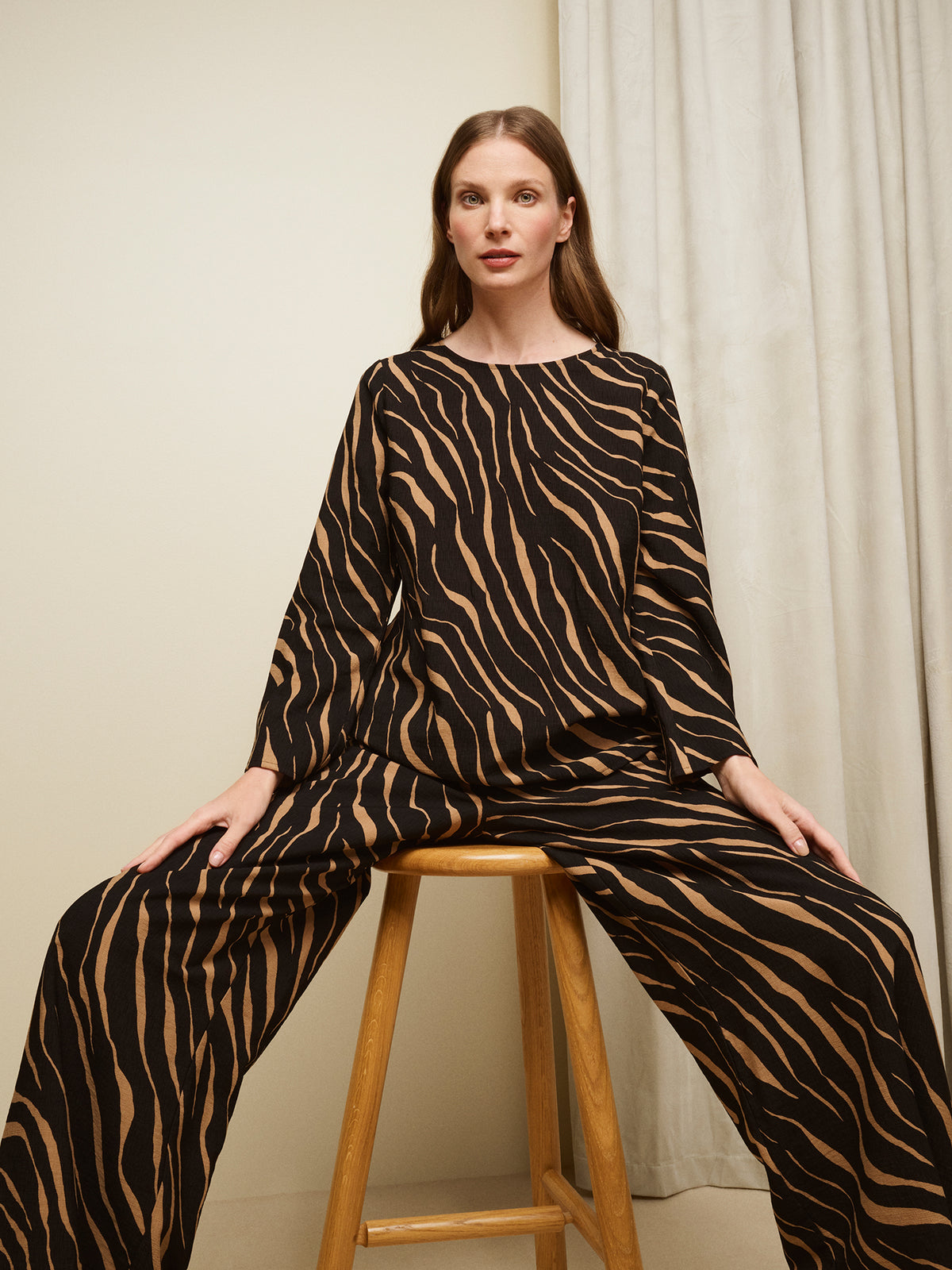 Nanso women's striking Sypressi belted blouse captivates with its elegant two-tone print, where shades of black and warm brown create a beautifully balanced look. Pictured on a model with matching trousers. | 36 - 175,5cm