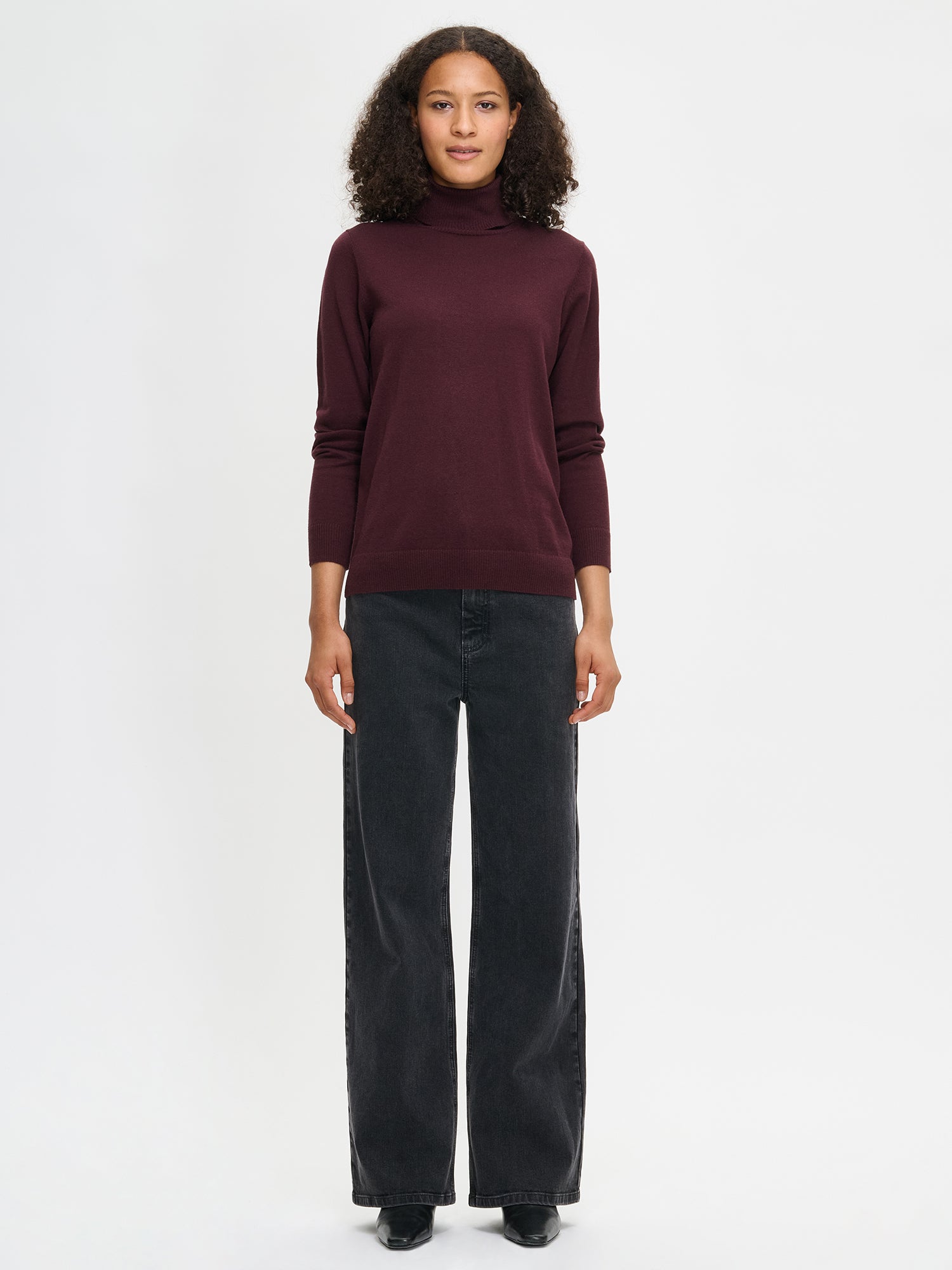 Nanso women’s dark red Villis turtleneck sweater in a lightweight merino wool and cotton blend, soft and breathable with full-length sleeves and hip-length hem, worn by model in full-body view.