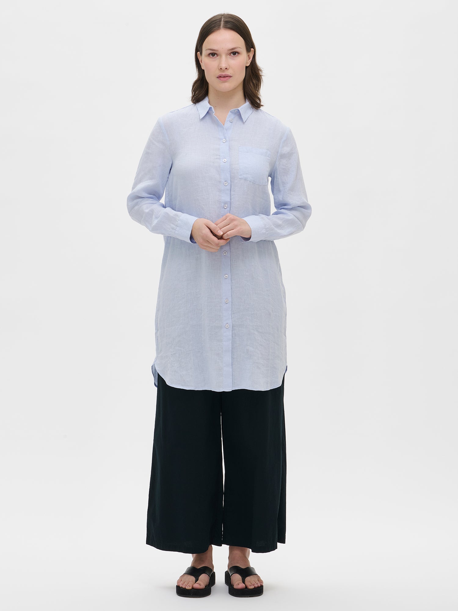 Nanso women's relaxed long light blue Pellava linen shirt paired with black trousers.