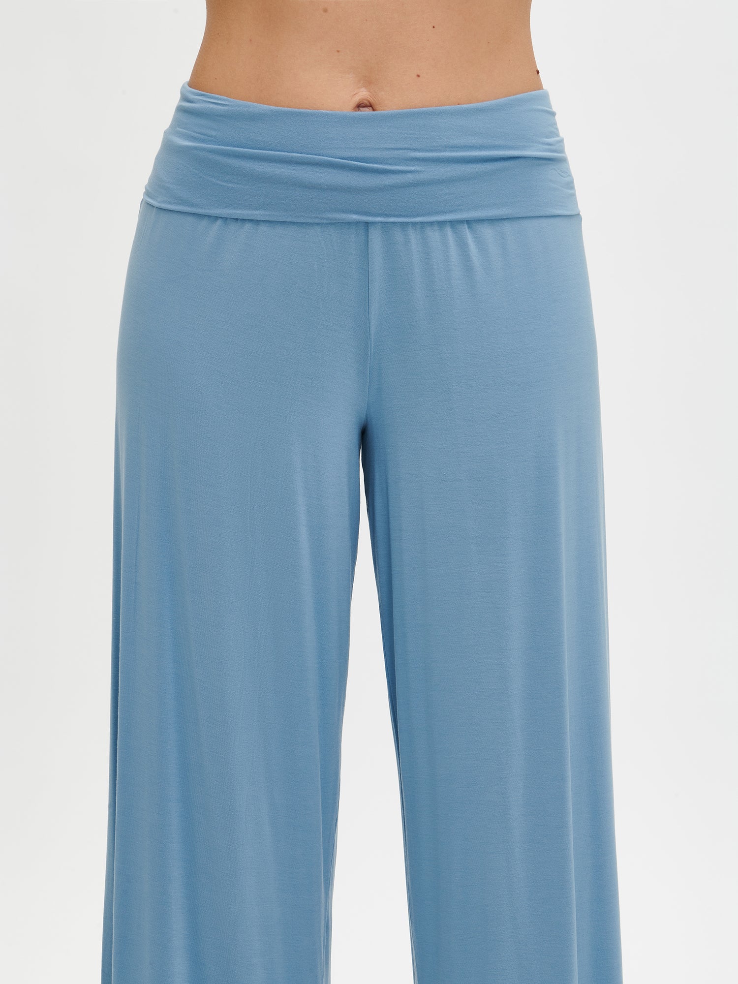 Nanson women's luxuriously soft solid blue Hento pants with a comfortable waistband and a wide, supportive double band, paired with the matching blue Hento top from the same collection, worn by the model in a close-up front view.