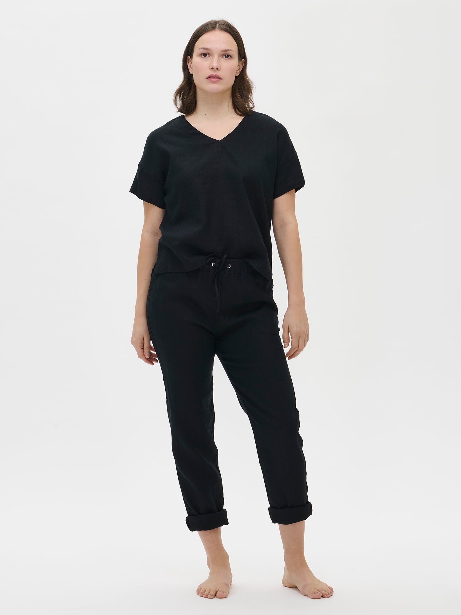 Nanso women’s black Sarastus linen trousers on the model, front view. Styled casually with a black T-shirt.
