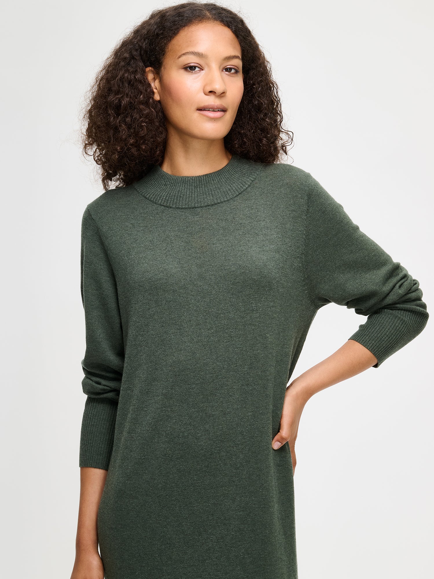 Nanso women’s dark olive green Villis knit dress in a merino wool and cotton blend, stand collar and long sleeves with ribbed details, worn by model in close-up view.