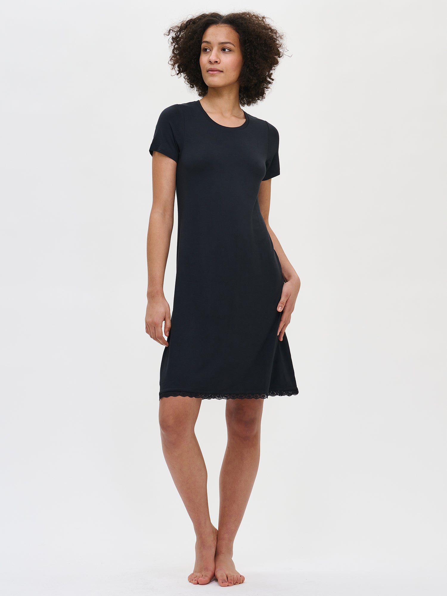 Nanso women's luxuriously soft black Pitsi nightgown with short sleeves, a round neckline, and a timeless lace-trimmed hem, worn by the model.