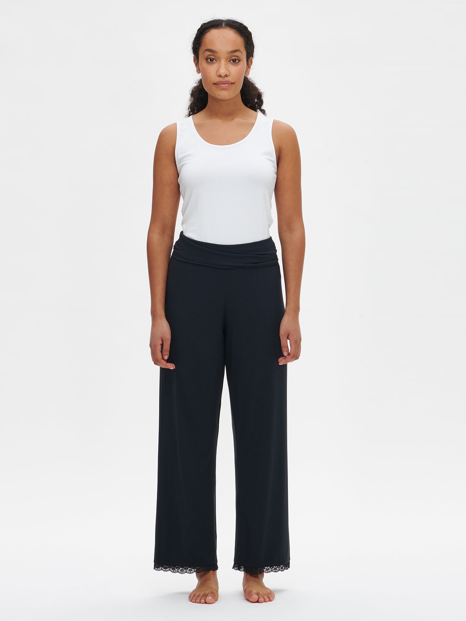 Nanson women's luxuriously soft black Pitsi pants, with timeless lace ribbons on the hems, paired with the matching Pitsi top from the same collection, worn by the model.