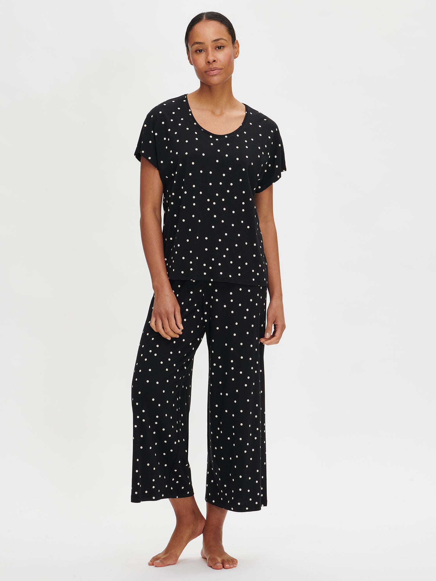 Nanson women's patterned purple 7/8-length Pallo pants, made from high-quality, soft cotton-modal that feels pleasant against the skin and is easy to care for, worn by the model with the matching black Pallo top from the same collection.