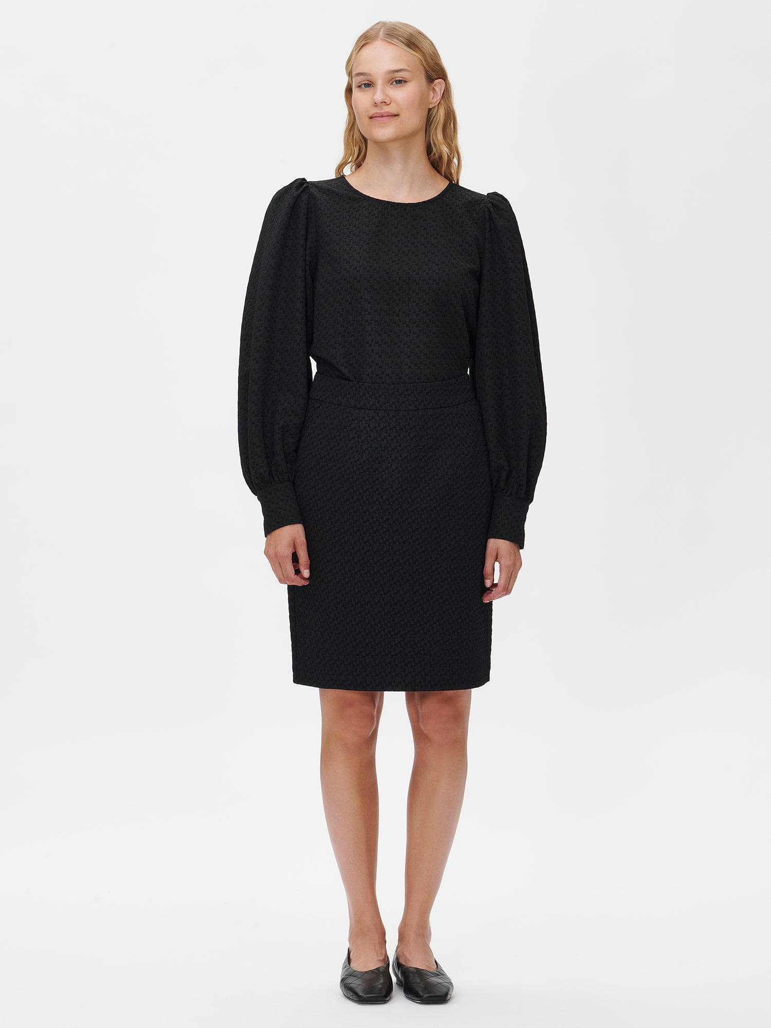 Nanso's stylish women's blouse in black features a beautiful textured surface. From the front styled with black reliefi skirt