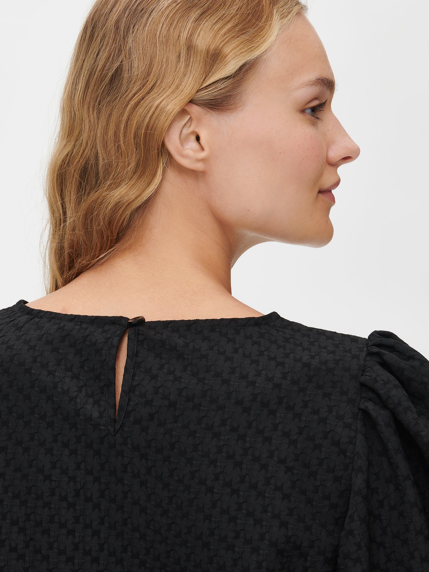 Nanso's stylish women's blouse in black features a beautiful textured surface. From the back