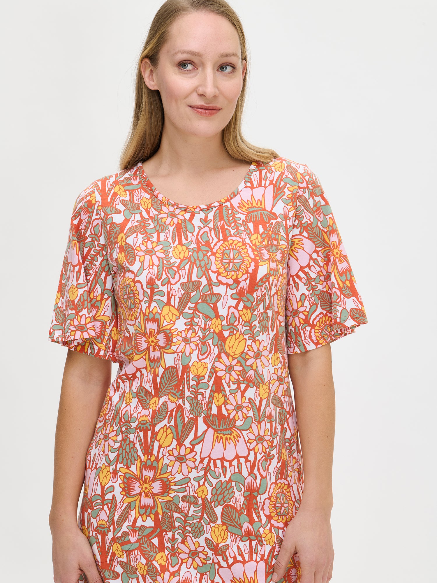 Nanso women's floral-printed, knee-length multicolored Oodi nightgown with short flared sleeves, a round neckline, and side pockets, worn by the model in a close-up front view.