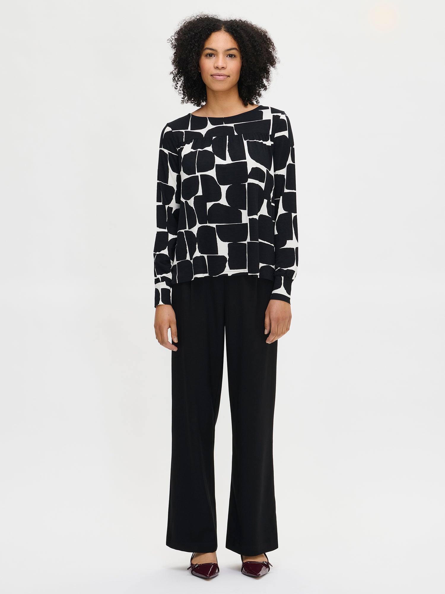 Nanso women’s black and white patterned Muuri top in viscose–elastane knit, relaxed fit with long sleeves, worn by model in full-body view.
