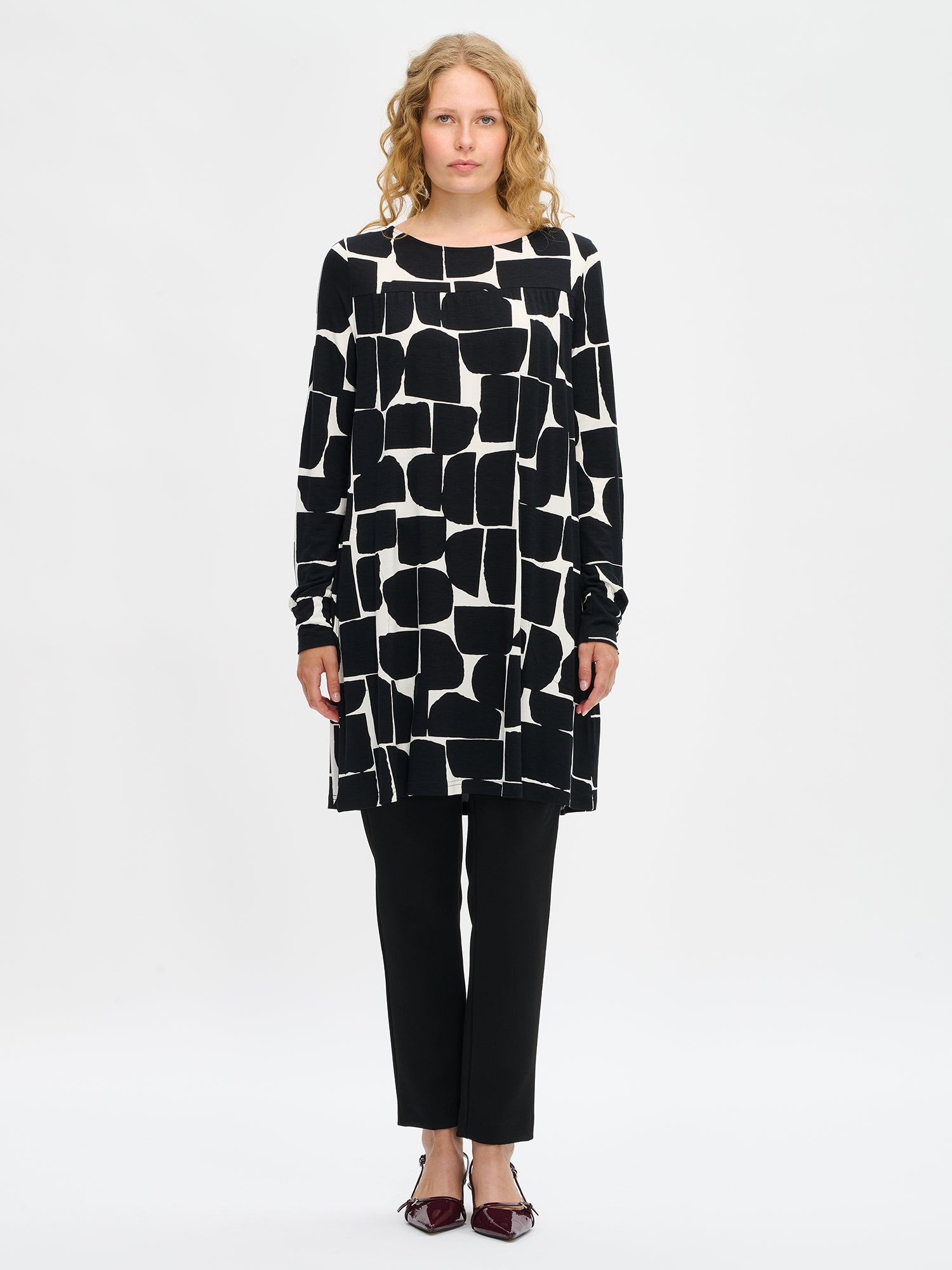 Nanso women’s black and white patterned Muuri tunic in viscose–elastane knit, round neckline, full-length sleeves and pockets, worn by model in full-body view.