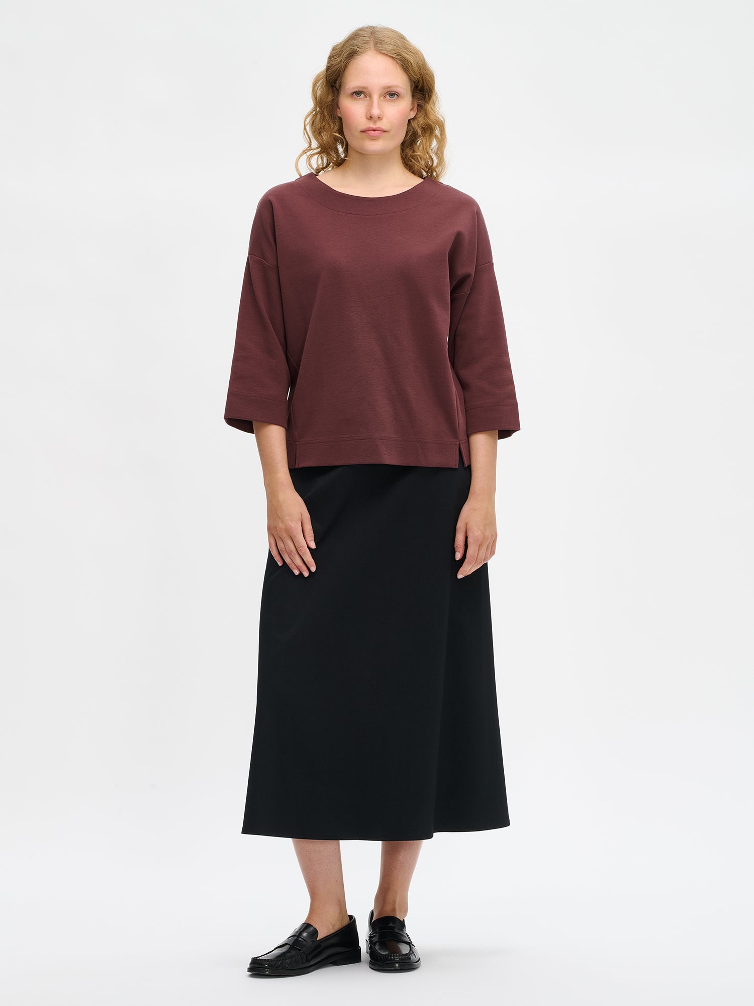Nanso women’s brown Elena top in cotton–polyester–elastane knit, oval neckline, 3/4 sleeves and dropped shoulders, worn by model in full-body view.