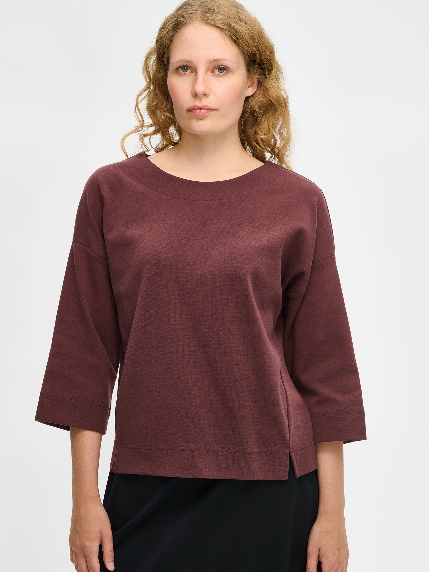 Nanso women’s brown Elena top in stretch cotton blend, oval neckline, 3/4 sleeves and side slits, worn by model in close-up view.