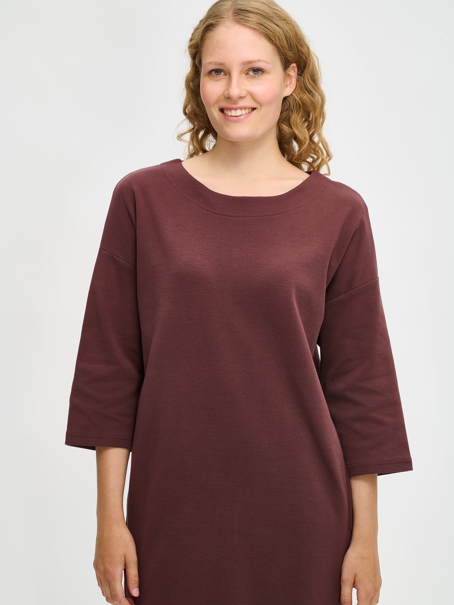 Nanso women’s brown Elena knit dress in stretch cotton blend, oval neckline and 3/4 sleeves, relaxed straight fit, worn by model in close-up view.