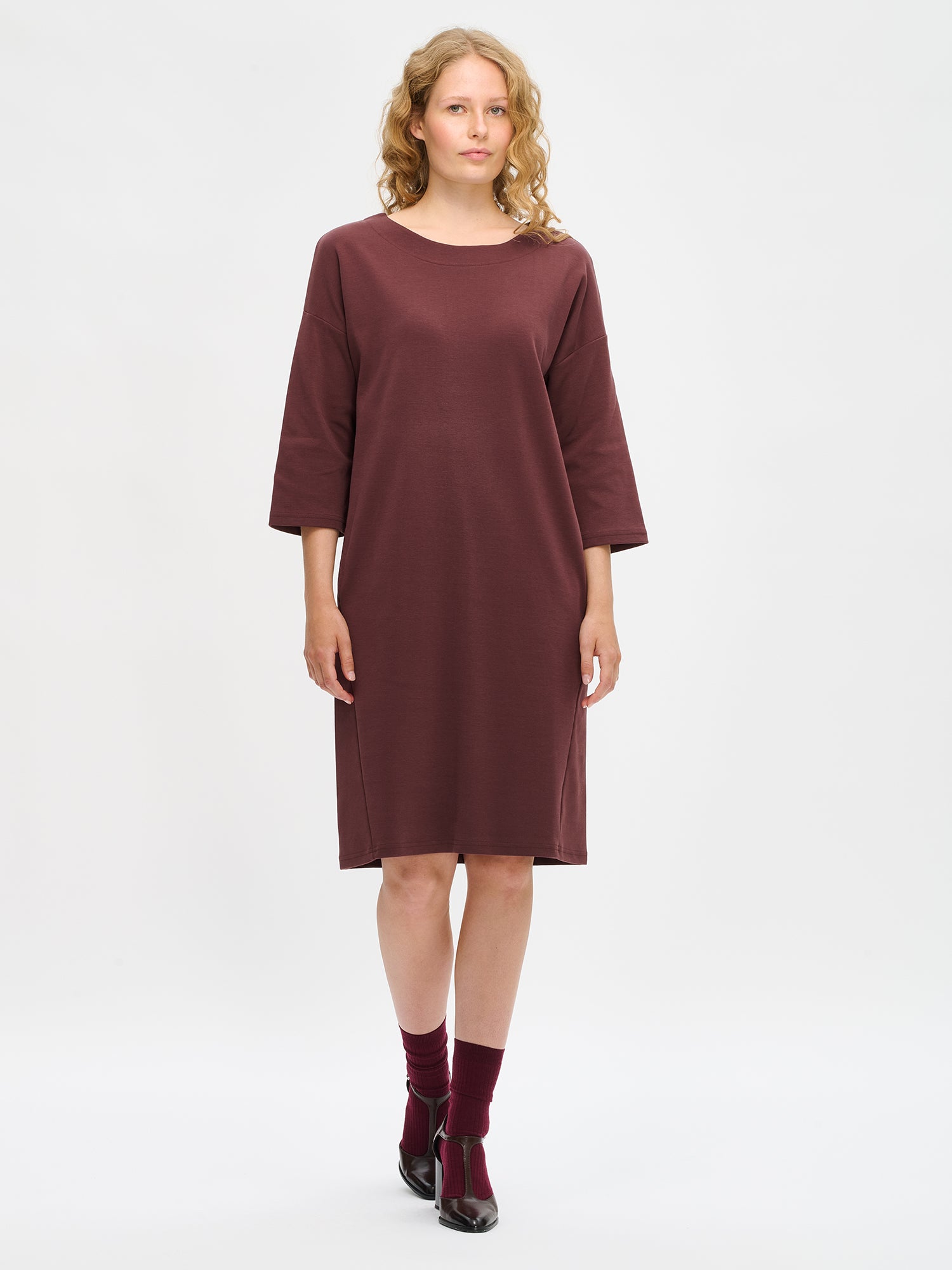 Nanso women’s brown Elena knit dress in cotton–polyester–elastane, oval neckline, 3/4 sleeves and dropped shoulders, worn by model in full-body view.